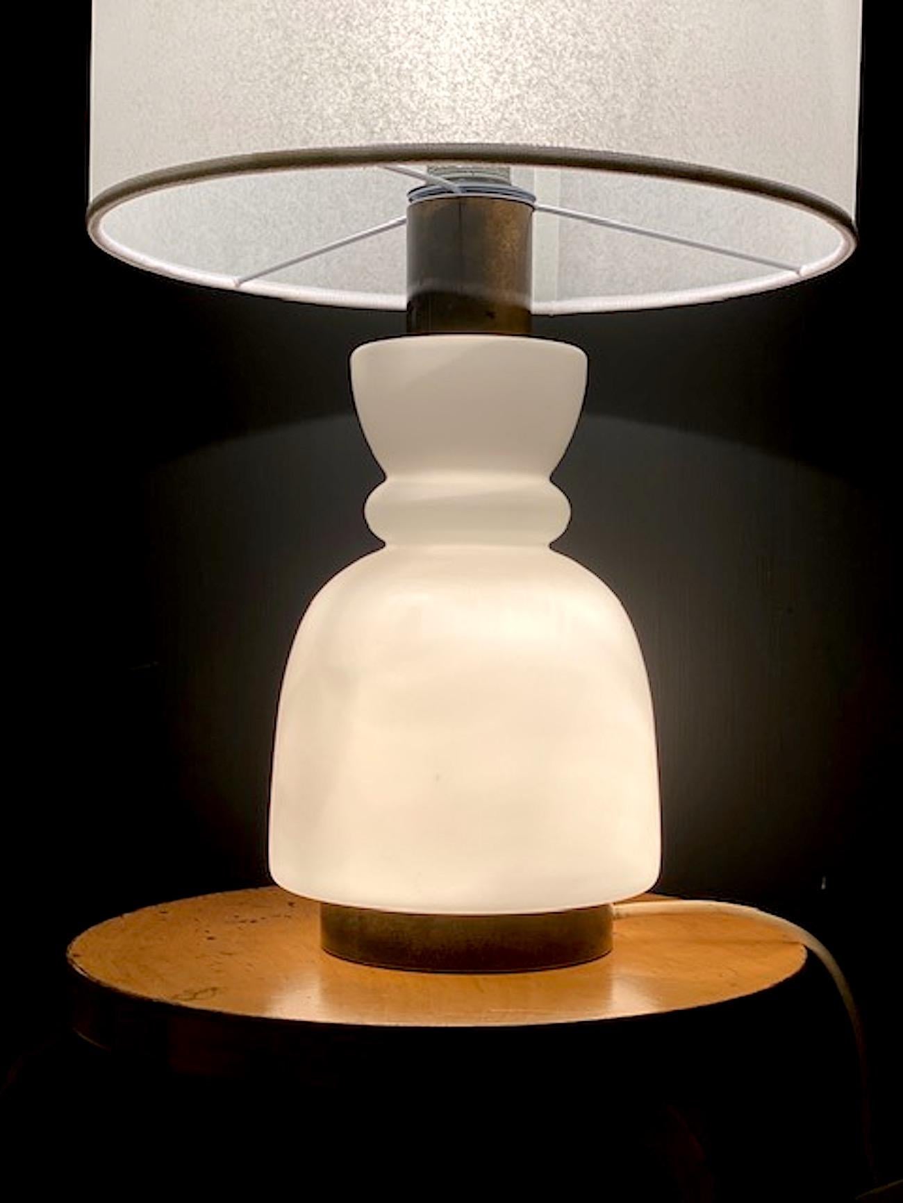 A late 1950s to 1960s Italian glass and brass table lamp attributed to the well known lighting company Stilnovo. The base lights up and is made of blown case glass in a vase shape. The lamp has brass mounts with original untouched patina.. Interior