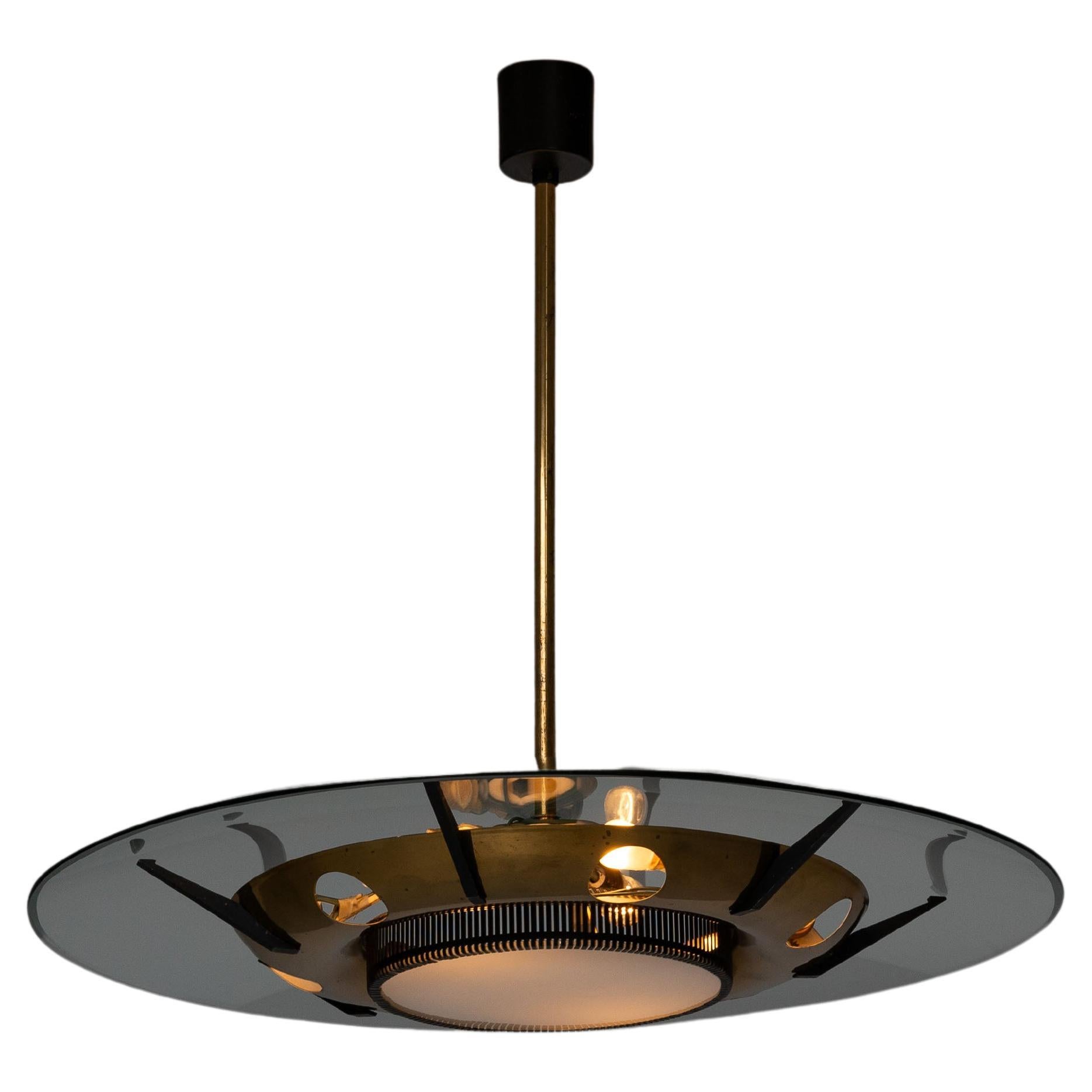 Unique saucer or UFO shaped chandelier designed and manufactured by Stilnovo in Italy in 1960. The lamp is made up of a brass stem supporting a clear glass circle that bends elegant over the structure. A brass round ring is supported by black metal