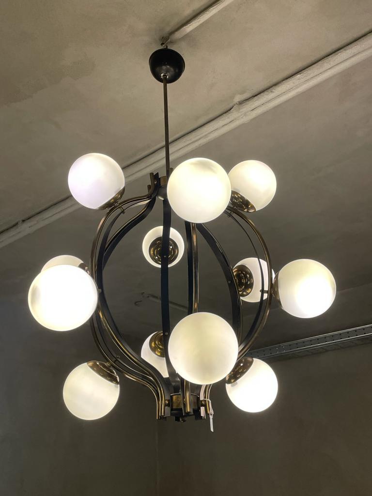 Chandelier manufactured by Stilnovo in Italy, 1960.
Structure in polished brass and black lacquered metal. It has twelve opaline satin glass balls.
The structure has six curved bars of brass and black lacquered metal, each of which precisely has