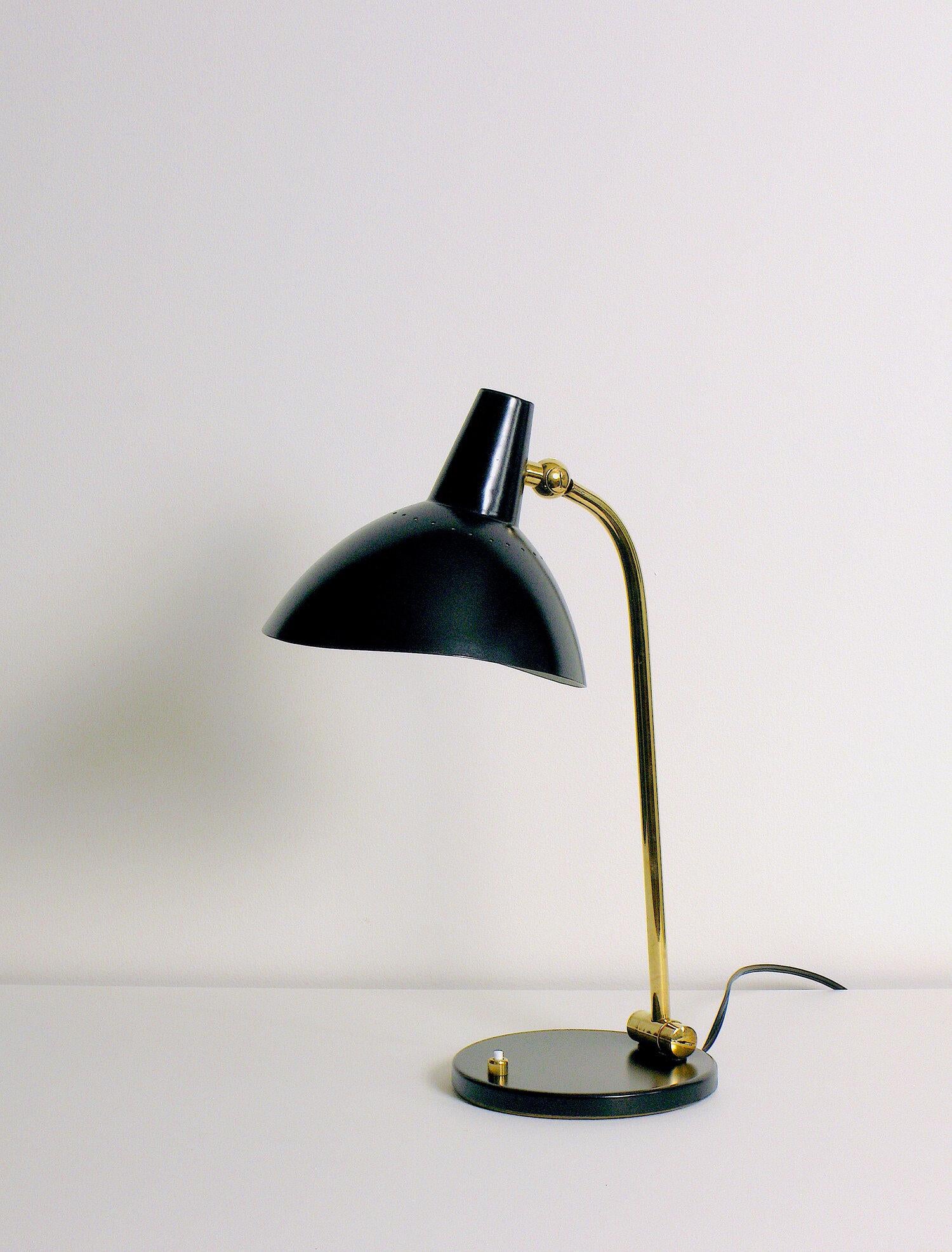 Lámpara de escritorio Stilnovo. Pantalla de aluminio esmaltado perforado negro, pivote giratorio de latón, vástago de latón, pivote de latón, pie de acero esmaltado y latón. Se recomienda una bombilla incandescente E-26 de 60 vatios con casquillo