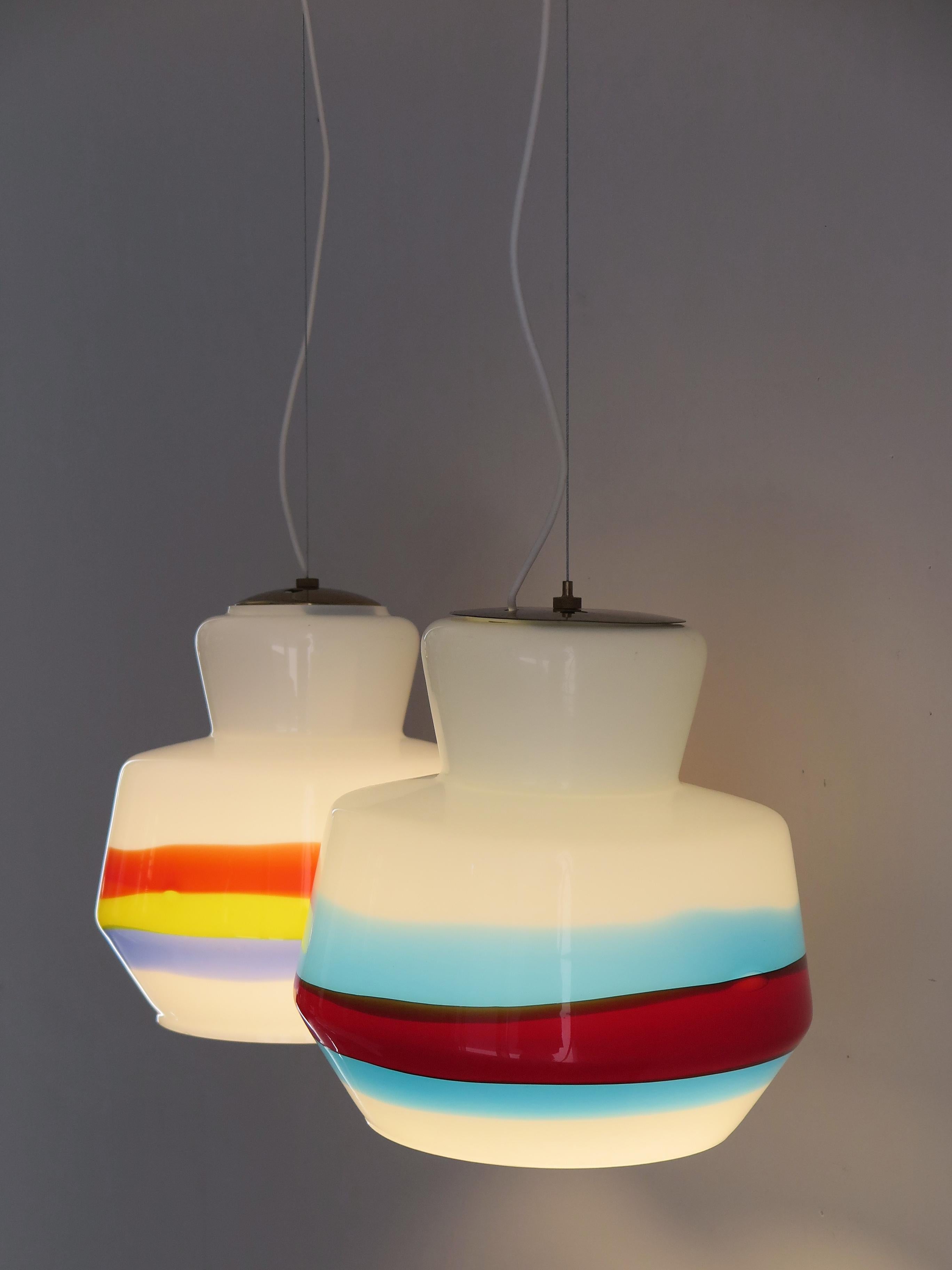 Couple of Mid-Century Modern design Italian glass pendant lamps produced by Stilnovo, glass diffusers and brass details, manufacturer's original adhesive labels, circa 1950s.

Please note that the lamp are original of the period and this shows
