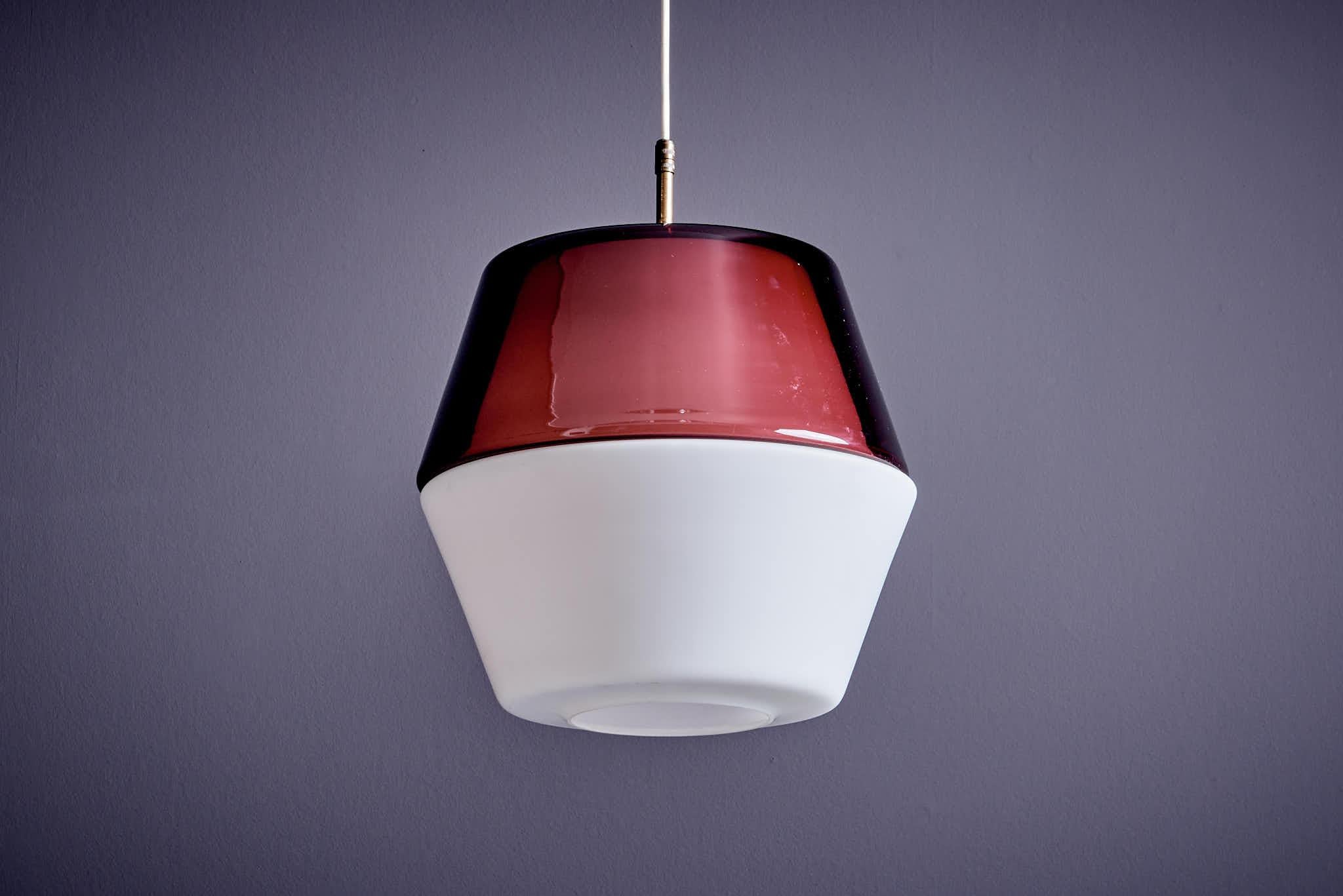 Pendant lamp with a brass frame and a two-piece glass shade, one of which is coloured. Made by Stilnovo in Italy around 1950. A striking mid-century design with timeless appeal.