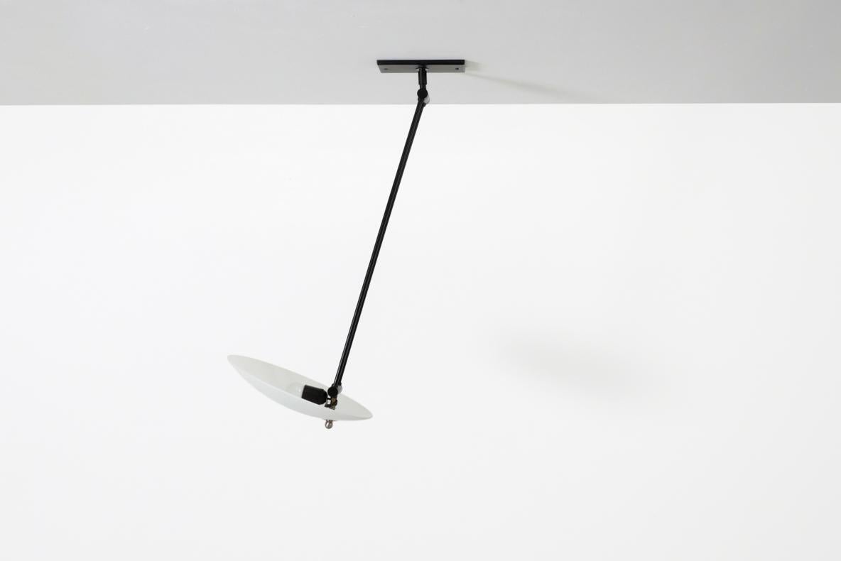 Modernist, Stilnovo inspired ceiling light with black enameled metal articulating arm and frosted glass disc shade. In original condition with visible wear consistent with it age and use.
