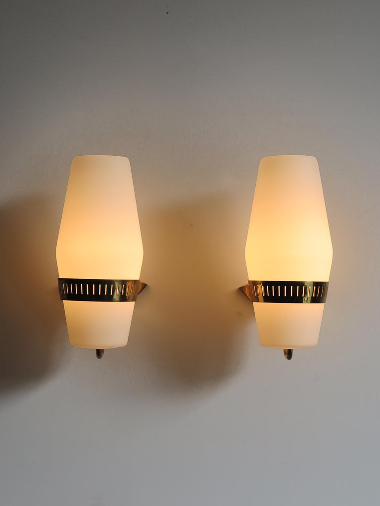 Italian Mid-Century Modern design large sconces wall lamps produced by Stilnovo from 1950s with white frosted glass diffusers and brass frame.
Adhesive manufacturer’s labels.

Please note that the lamps are original of the period and this shows