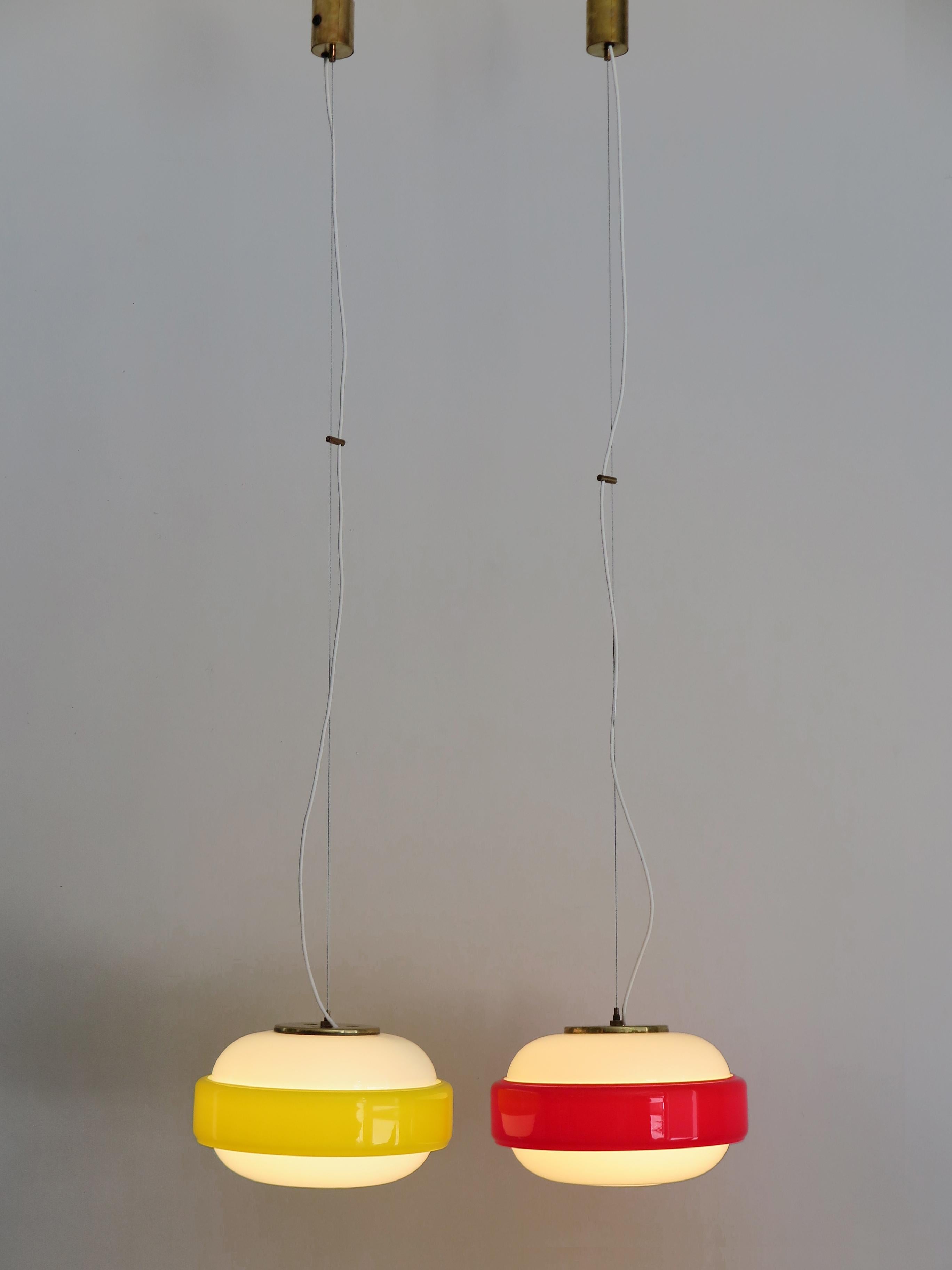 Set of two of Italian amazing pendant lamps or hanging lights produced by Stilnovo from 1960; brass, white opaline glasses and incamiciato yellow and red glasses; original Stilnovo label, circa 1960s.

Please note that the lamps are original of