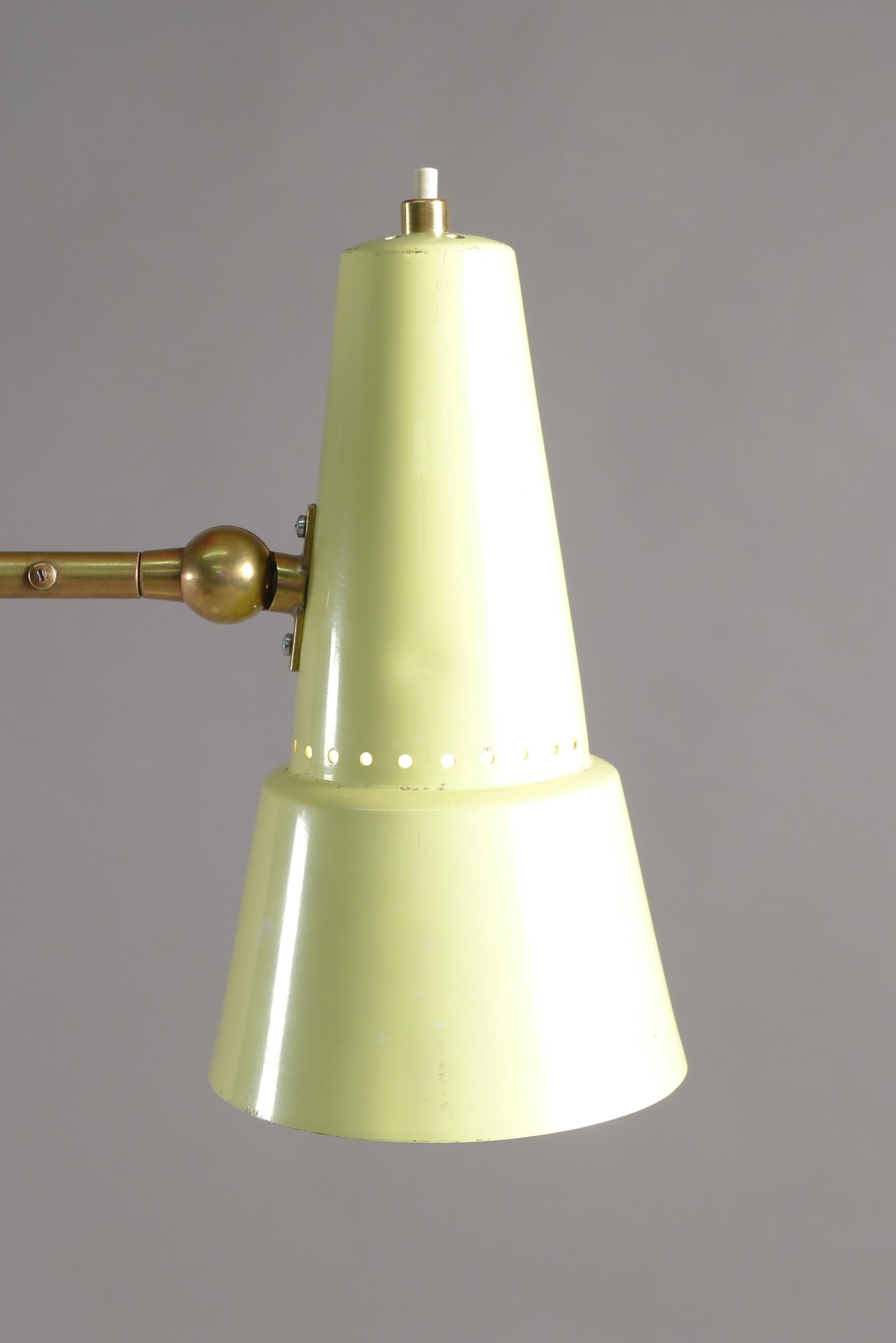Stilnovo, Italy, circa 1955. A floor lamp with marble foot supporting an angled upright stem with large red uplighter on top and a pivoting brass arm terminating in a yellow enamelled shade which pivots in all directions.
The stem is angled near