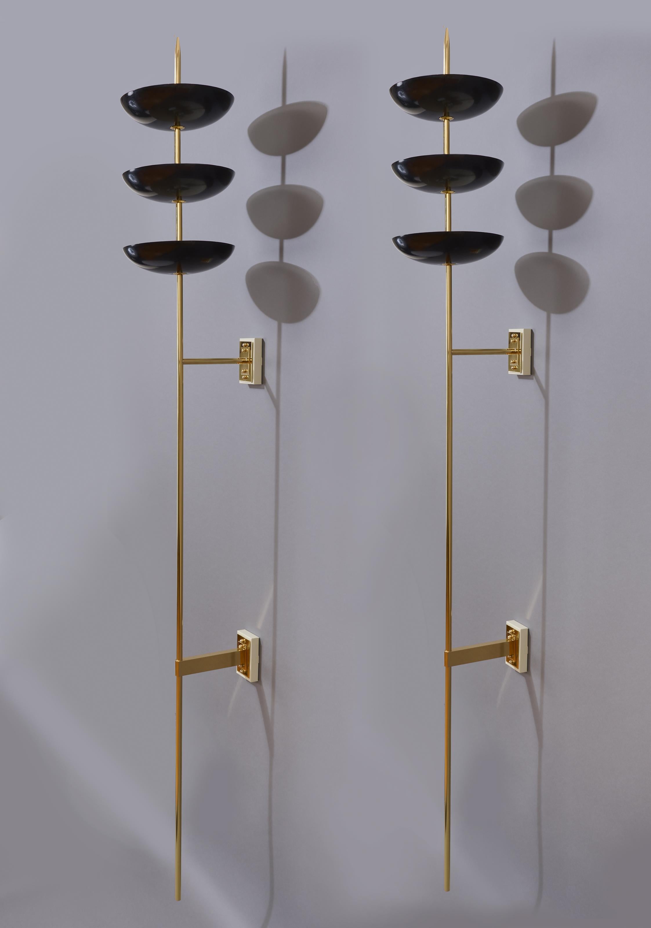 Stilnovo

A monumental pair of spear-like, seven and a quarter foot tall sconces by Stilnovo. Three shallow bowls, in black enamel with white interior, float on the upper third of a polished brass shaft with a long and pointed finial. The sconces