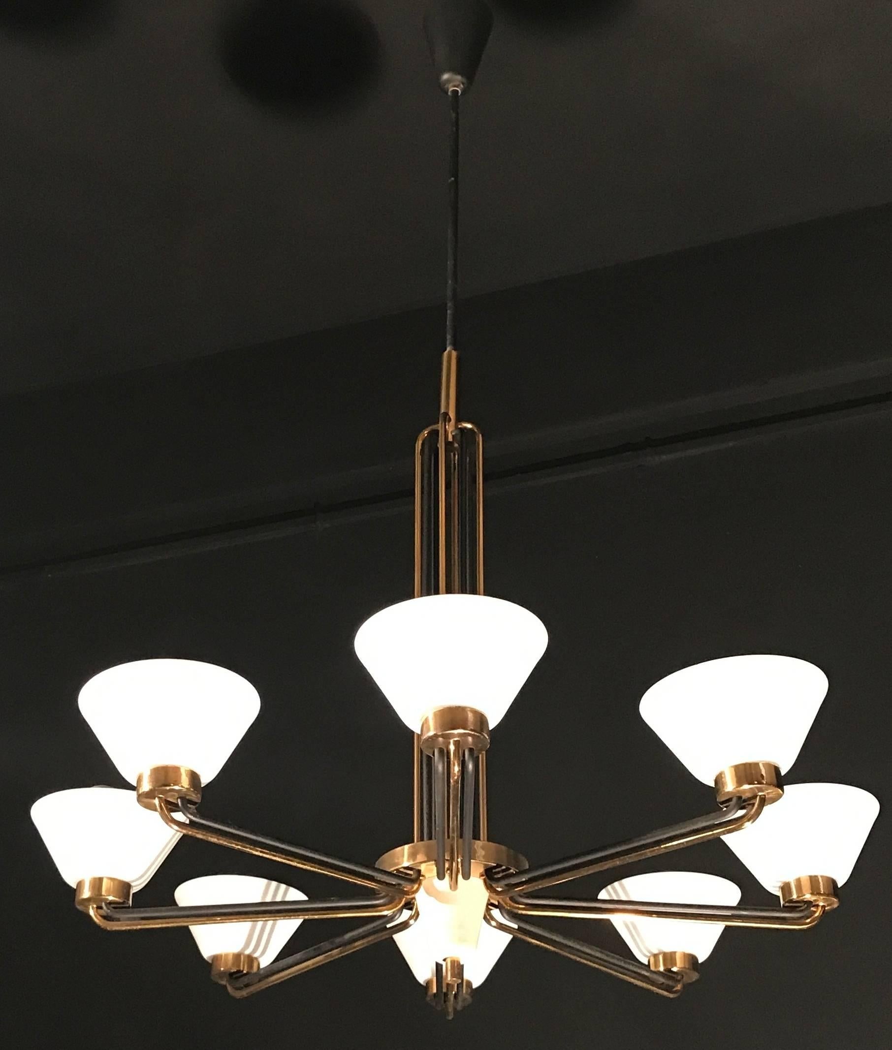 Linear elegance, brass and black painted eight arms chandelier, holding upturned opaline glass shades. Excellent vintage condition.
Eight E 27 light bulbs.
    