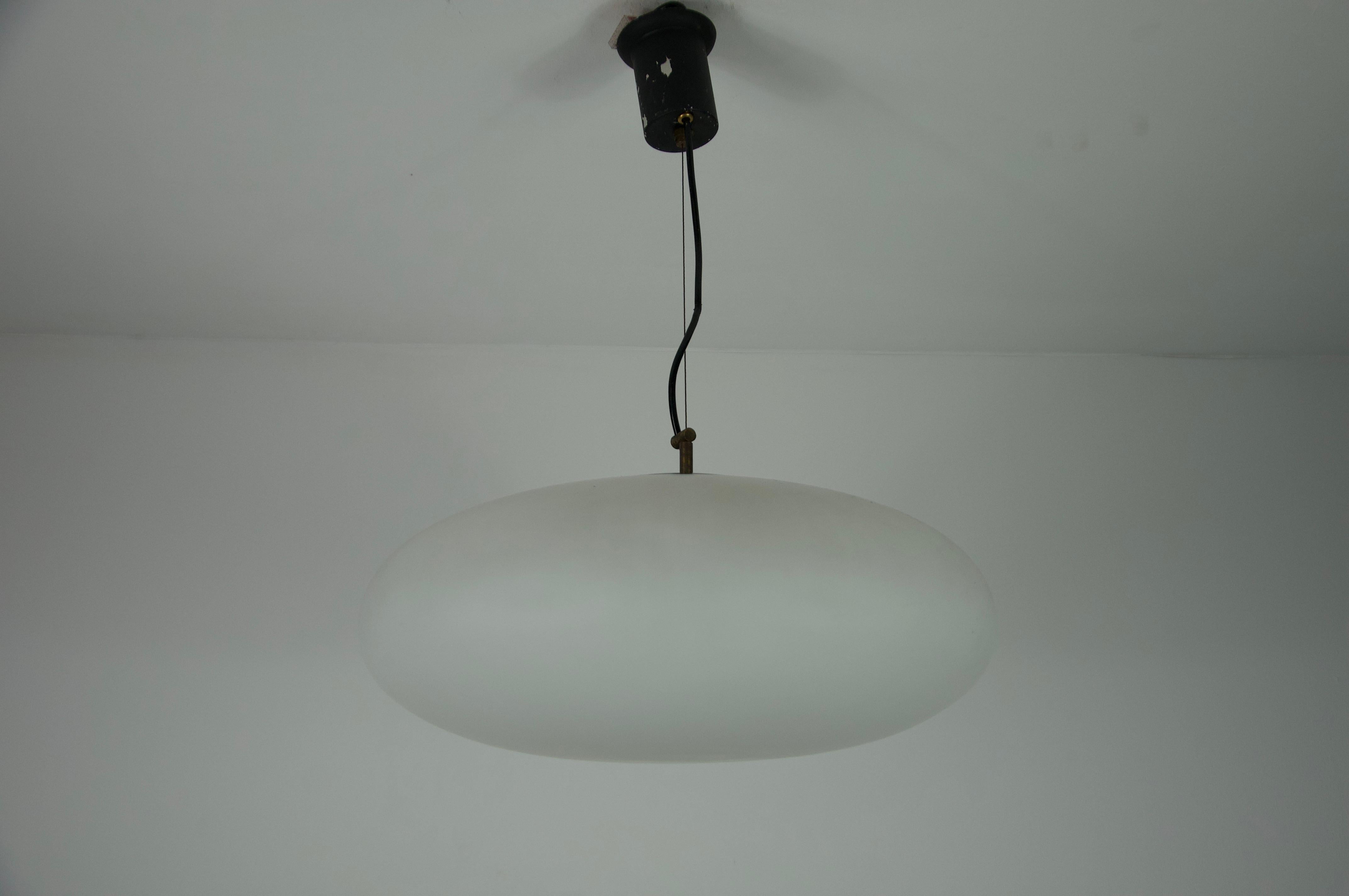 Ce plafonnier moderne du milieu du siècle du célèbre fabricant italien Stinero, datant des années 1950, est un chef-d'œuvre d'élégance intemporelle. La lampe est dotée d'un abat-jour en verre opale de forme ovale, qui émet une lumière chaude et