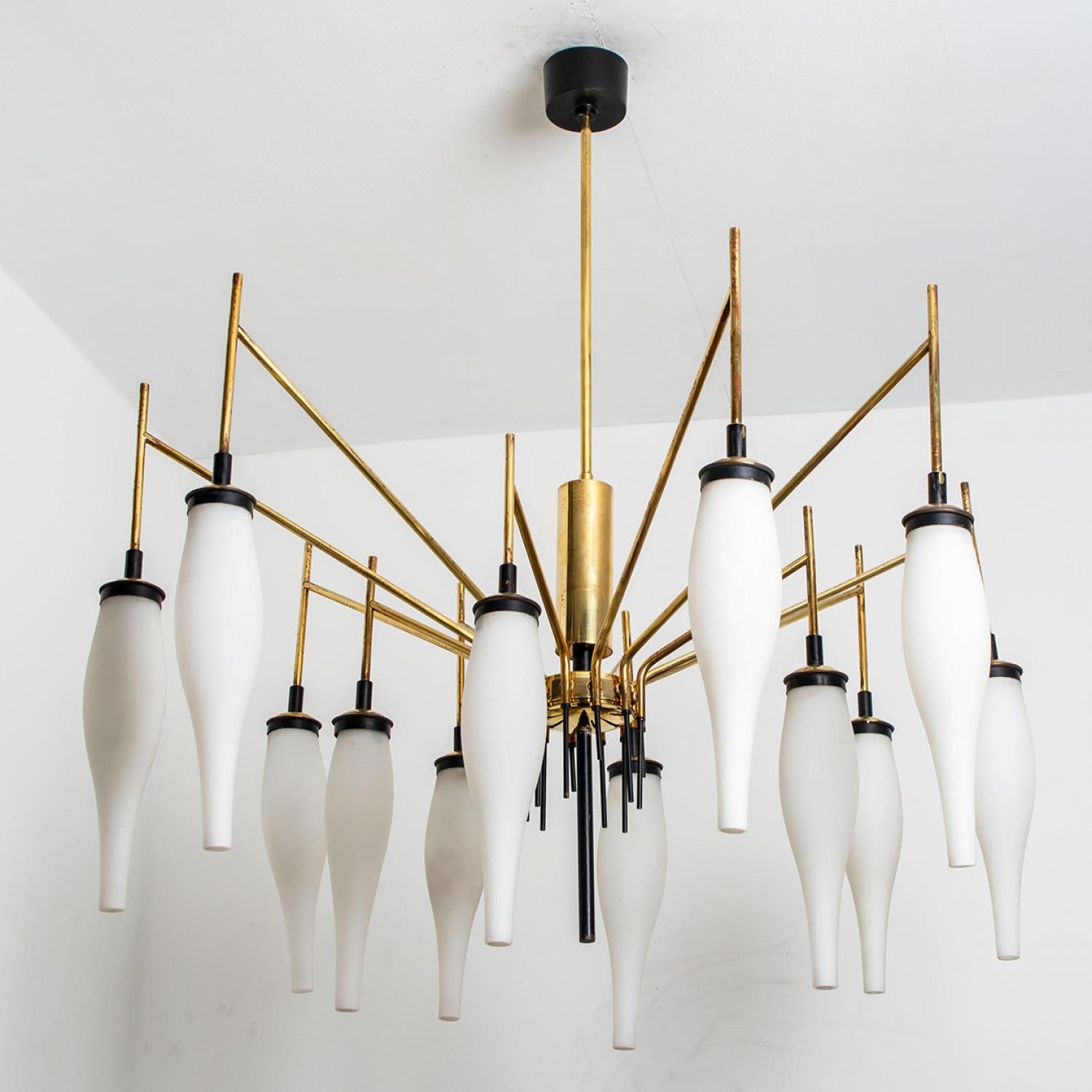 Playful brass and milkglass chandelier designed by Stilnovo. Manufactured in Italy, around 1960. This magnificent chandelier has a beautiful shape and is richly decorated with crystal drops. The chandelier is made of a brass frame with 12 arms