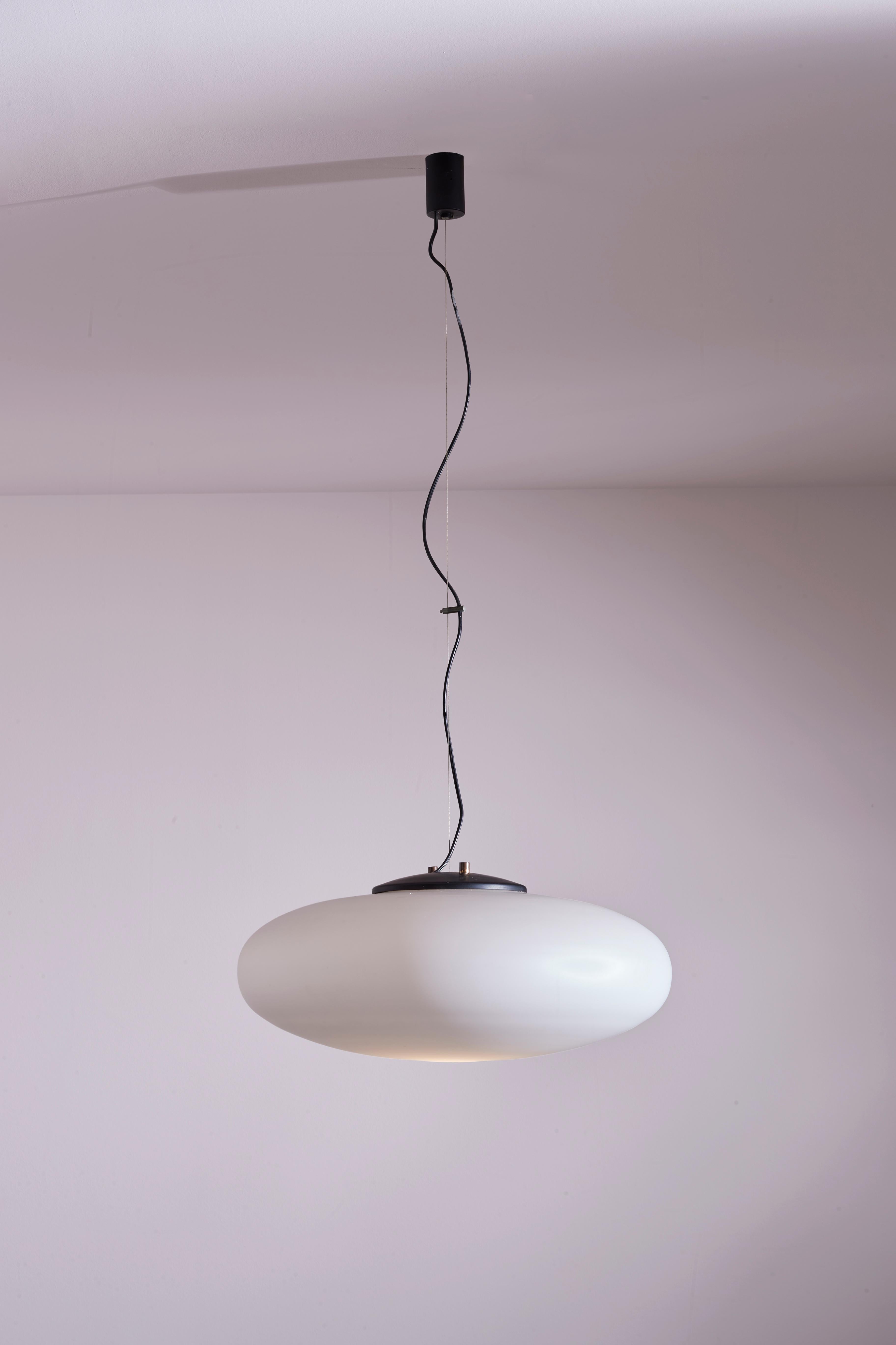 Large chandelier in white opaline glass and painted metal, model 1104, from the 1950s, produced by Stilnovo.

A grand, sinuous oval shape suspended by a thin cable. This ceiling light has the ability to become the centerpiece of a room, thanks to