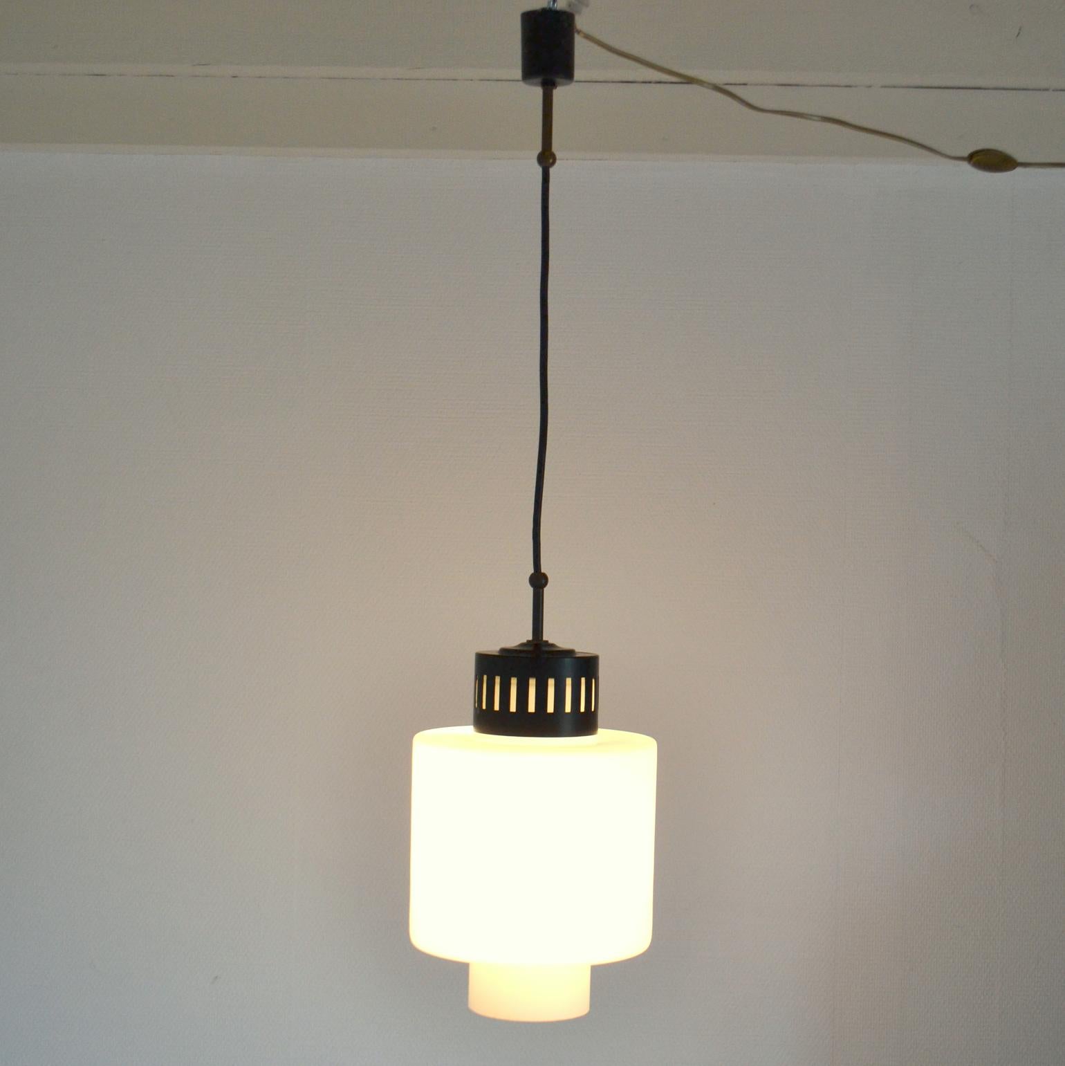 Classic Stilnovo 1960's pendant in milk glass edged with a metal rim hanging from a black metal and brass lamp holder.
This lamp is very functional for general light and most suitable for a small room.
Similar Stilnovo lamp available to combine in