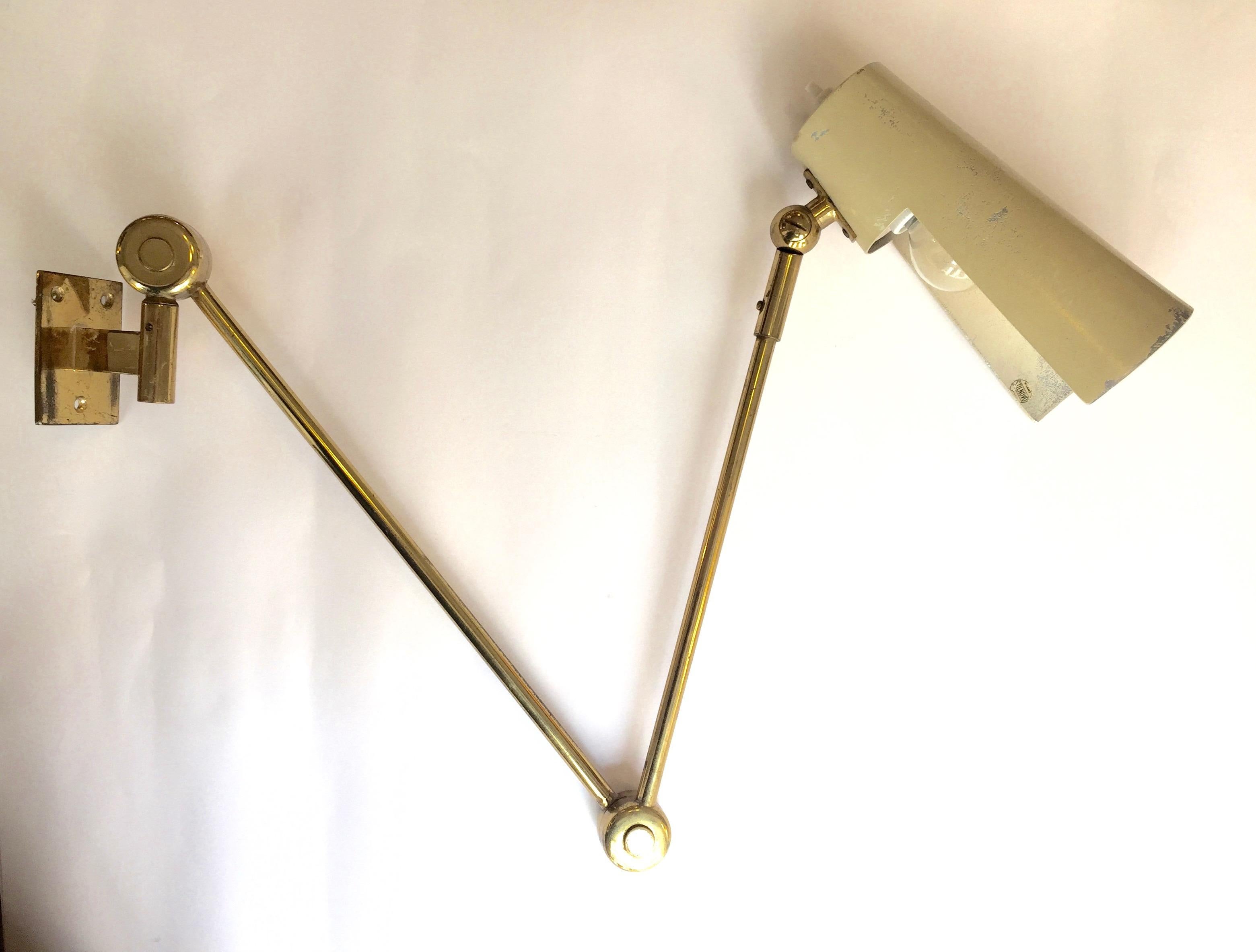An original brass and enameled metal wall lamp, adjustable arm. Edited by Stilnovo. Stamped.