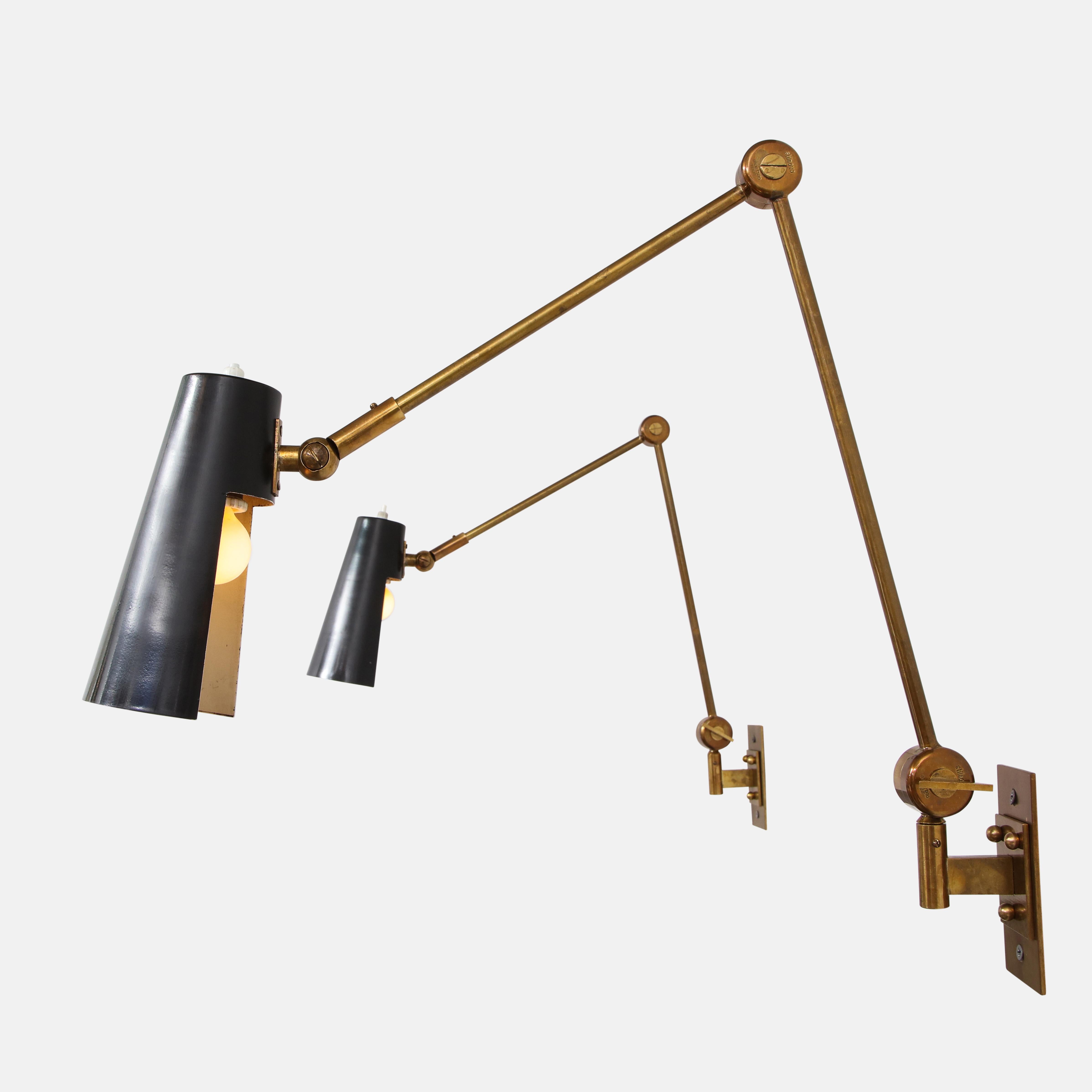 Stilnovo pair of articulating wall lights model 2024 with black enameled perforated metal shades on brass arms. The metal shades pivot from ball joints and the articulating arms are adjustable from butterfly keys. Beautifully designed and executed,