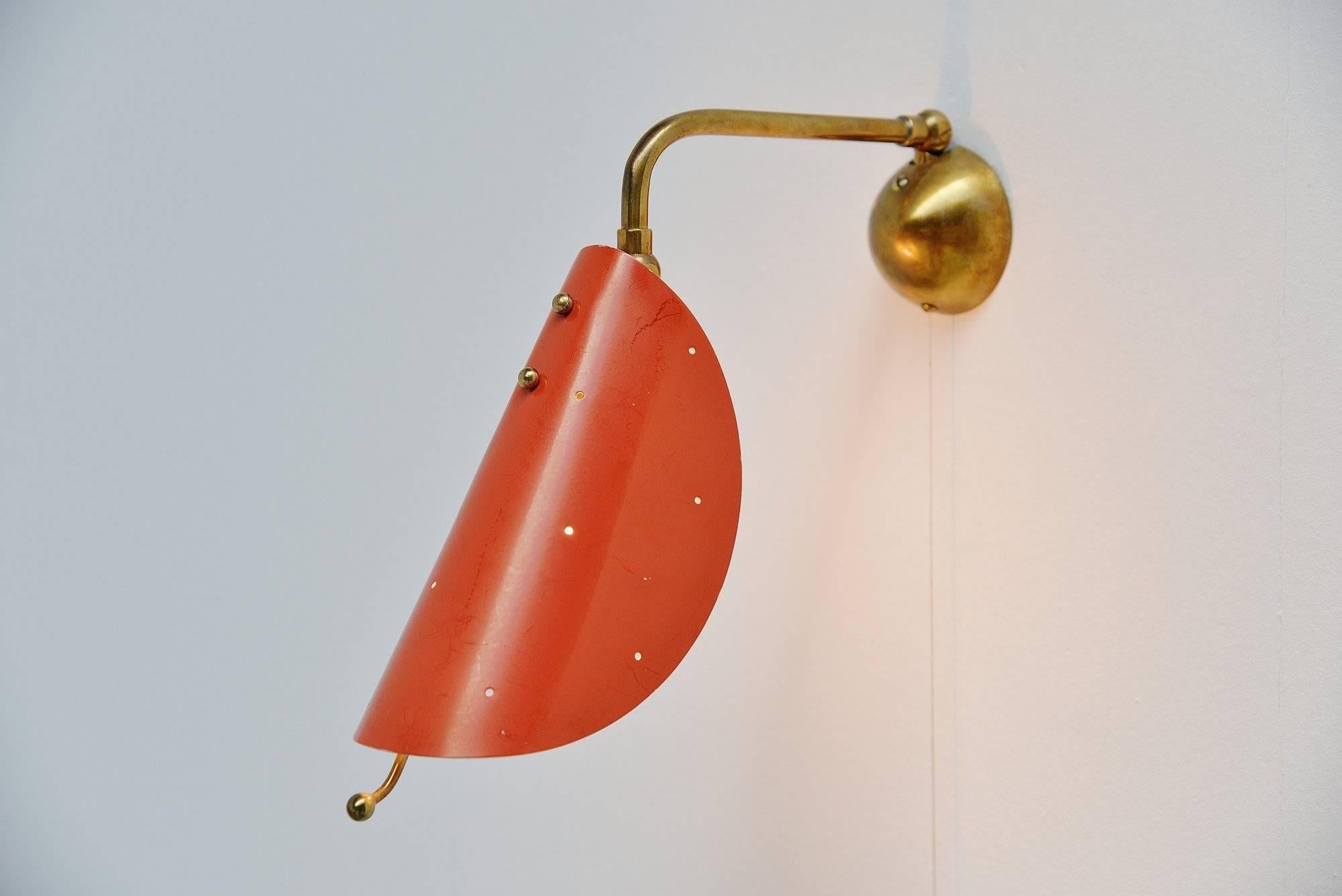 Very nice pair of sconces attributed to Stilnovo Italy in 1950. These lamps have brass arms adjustable and orange shades with die cut pattern all over. A very nice detail is the handle to adjust the sconces to get different diffused light. The lamps