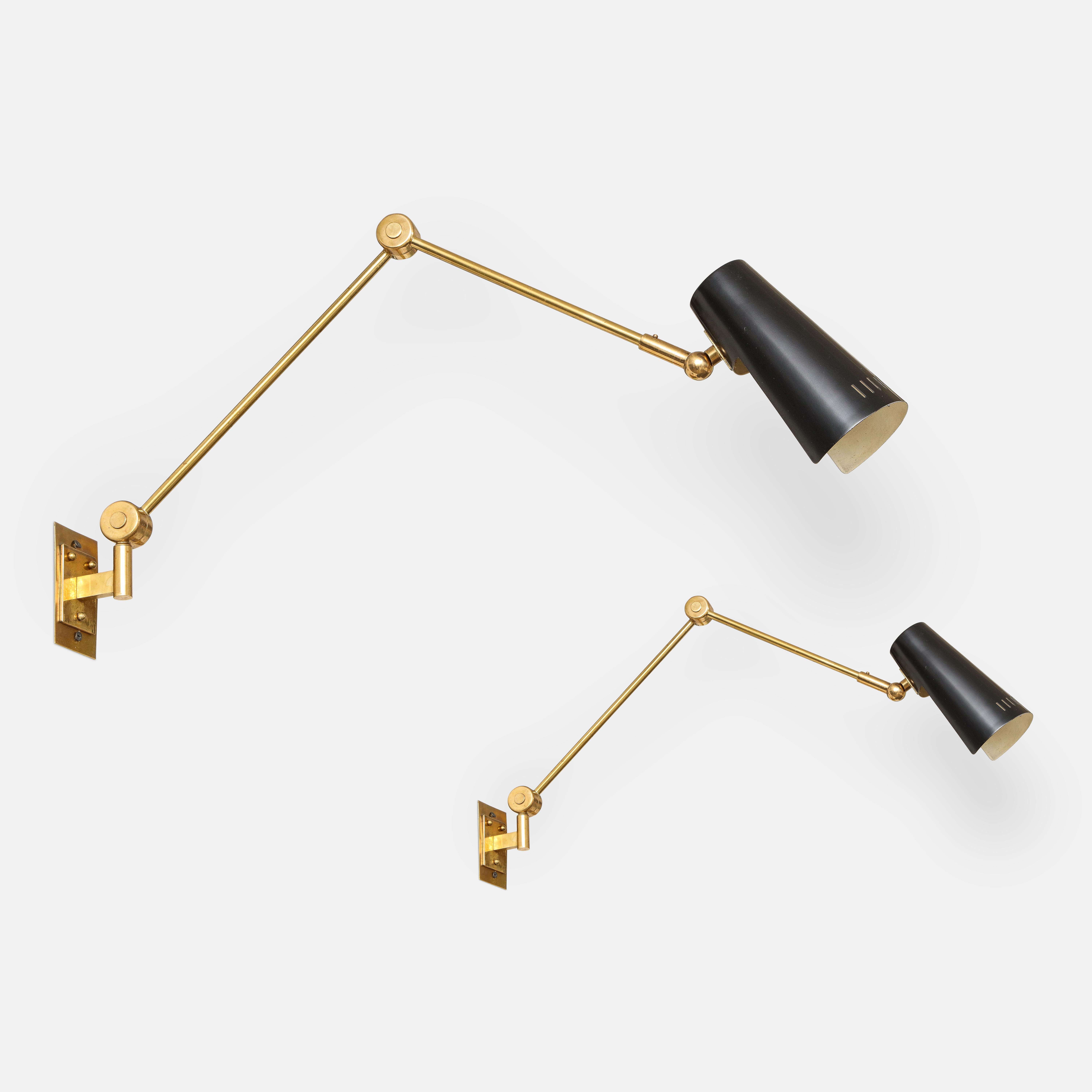 Stilnovo pairs of articulating wall lights model 2024 with original black enameled perforated metal shades on brass arms, Italy, 1950s. The metal shades pivot from ball joints and the articulating arms are adjustable from butterfly keys. Beautifully