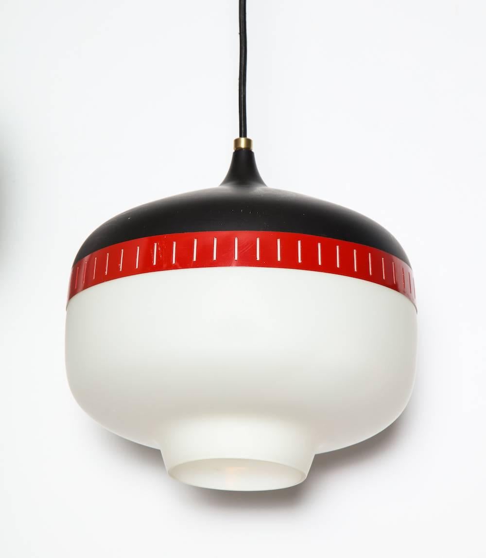 Stilnovo double pendant light.
Beautifully shaped satin glass shades, each concealing one standard sized socket. Black and red lacquered metal caps to each shade, and center brass 