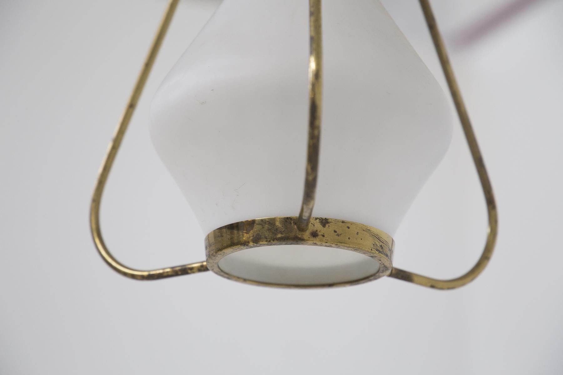 Splendid pendant of Stilnovo design made in opaline glass and brass, in the 1960s. The chandelier connects to the ceiling with a semicircular black aluminum element; the stem is made in the form of a gold-plated brass chain, which attaches to the