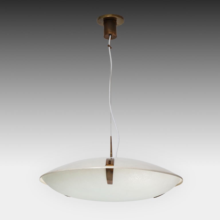 Stilnovo pendant or suspension light model 1140 with white enameled aluminum shade suspending textured glass dome shade with brass fittings and suspended from its original brass canopy with custom ceiling plate. This Stilnovo model is strikingly