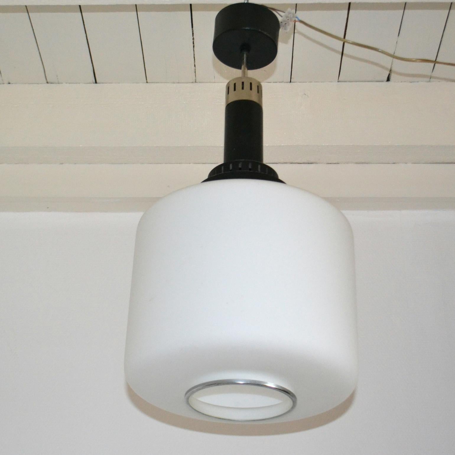 Classico ciondolo Stilnovo degli anni '60 in vetro lattimo bordato con un bordo in metallo che pende da un portalampada in metallo nero e ottone.
Questa lampada è molto funzionale per l'illuminazione generale e più adatta a una stanza piccola.
Una