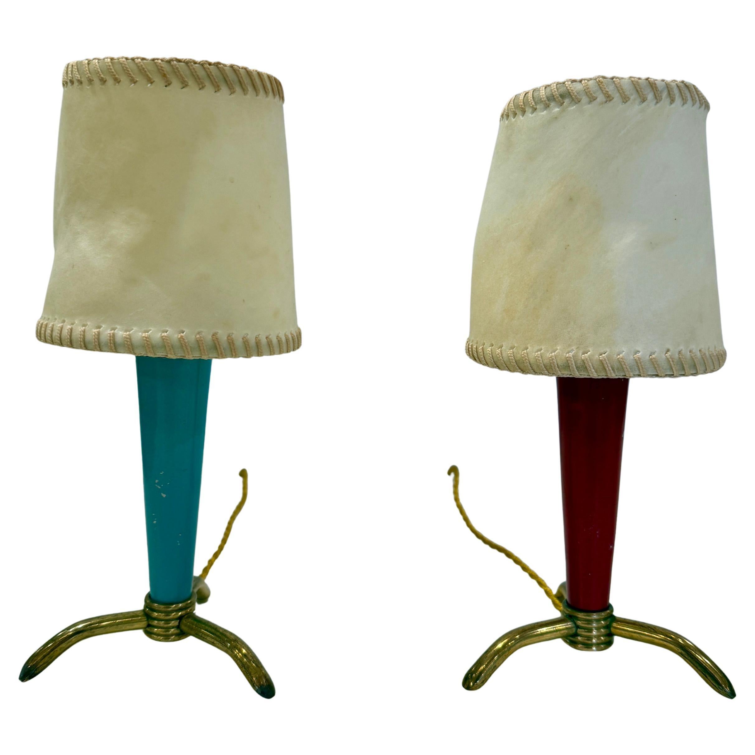 Attributed to Stilnovo, these lovely petite lamps are so cute and burst of personality - they would fit perfectly on a bookshelf, library, boudoir, kids room, etc.  They have a tripod brass base and original painted blue and red tapering bodies. 