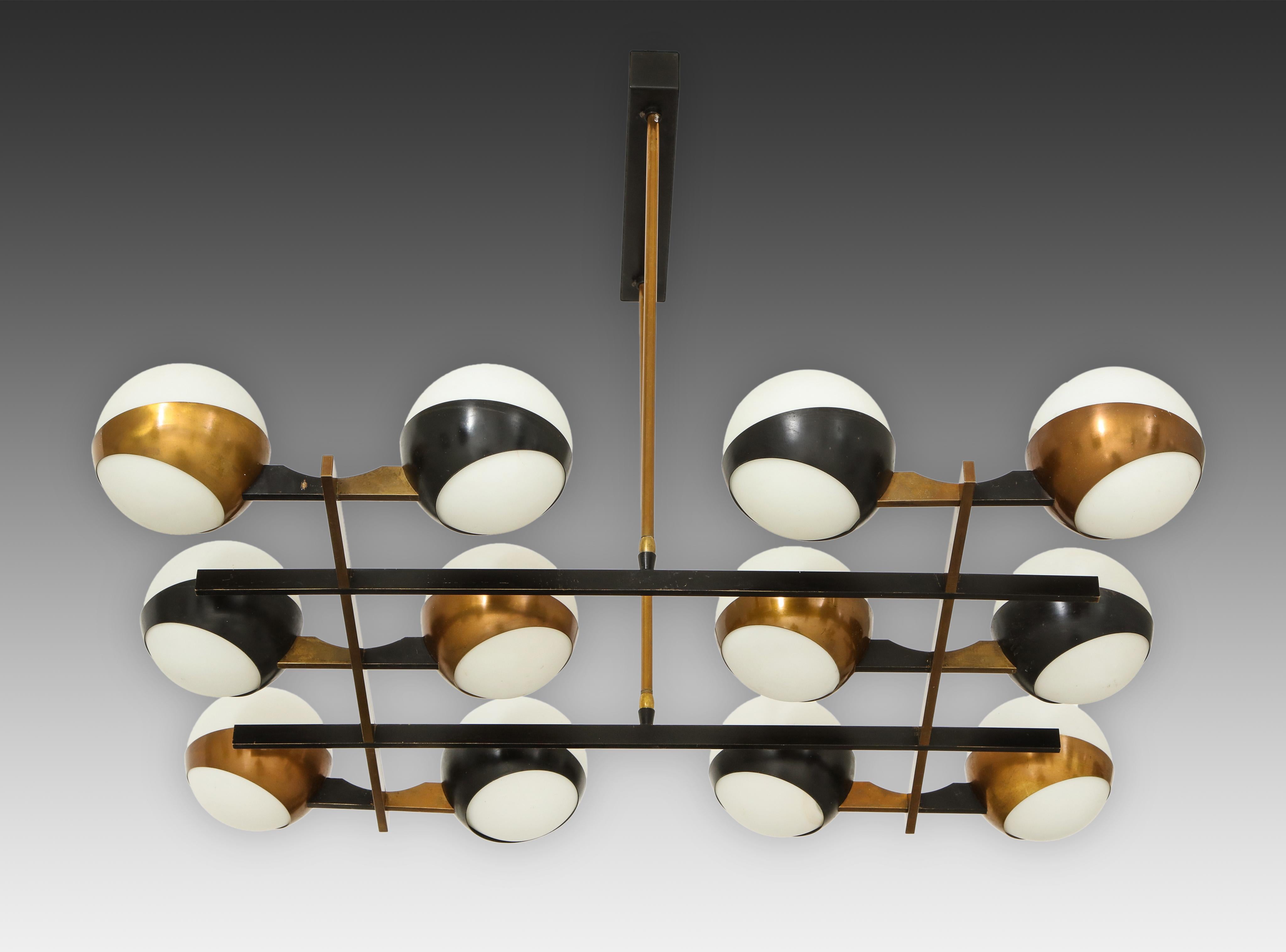 Stilnovo chandelier with twelve-opaque glass globes held in brass rings with alternating rings painted black on architectural grid-like structure. The structure is suspended by two brass rods on a black painted rectangular metal canopy. This