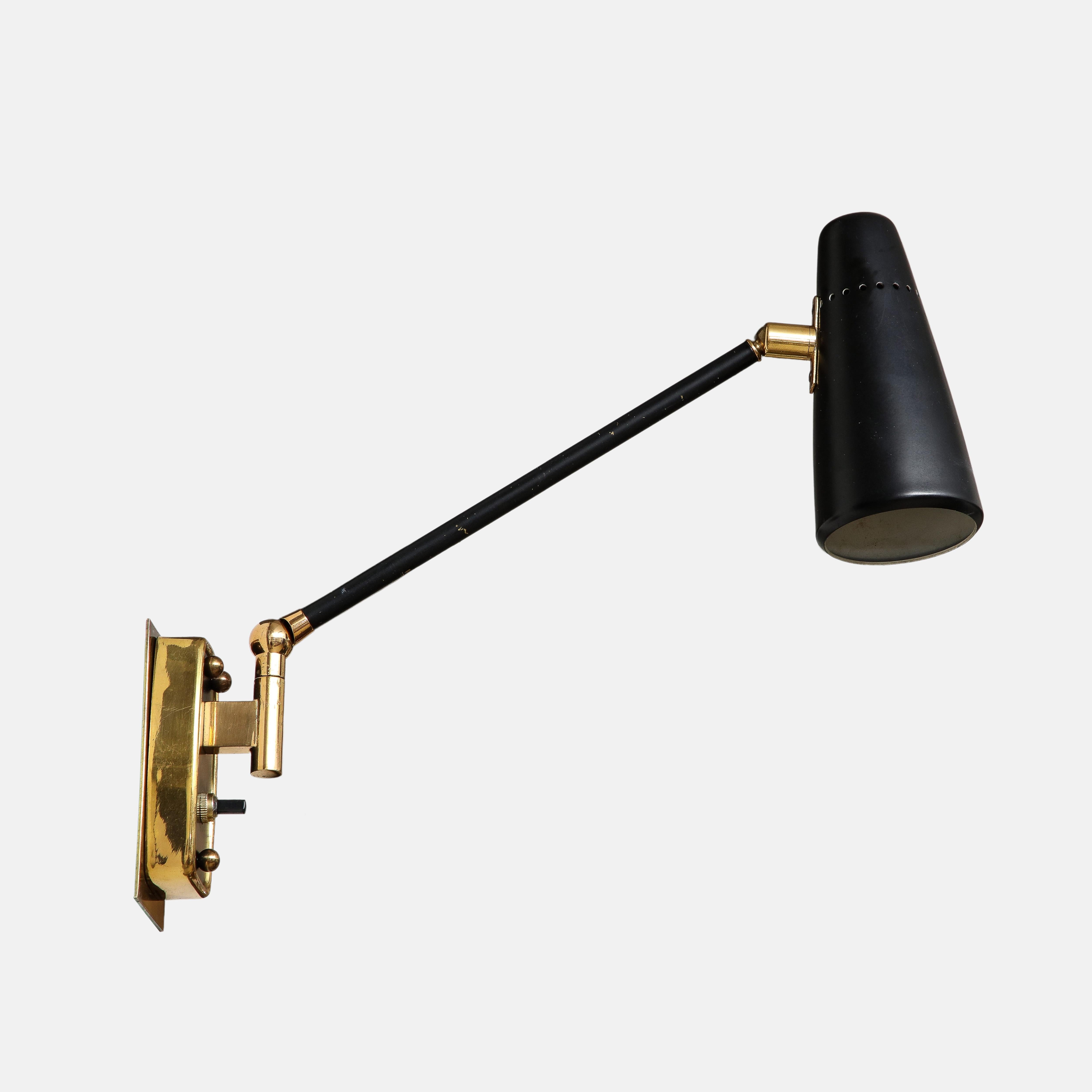 Stilnovo rare pair of articulating sconces, wall lights, or reading wall lights with pivoting black enameled perforated metal shades on brass arms. The metal shades and arms or stems pivot from ball joints and are attached to the original backplates