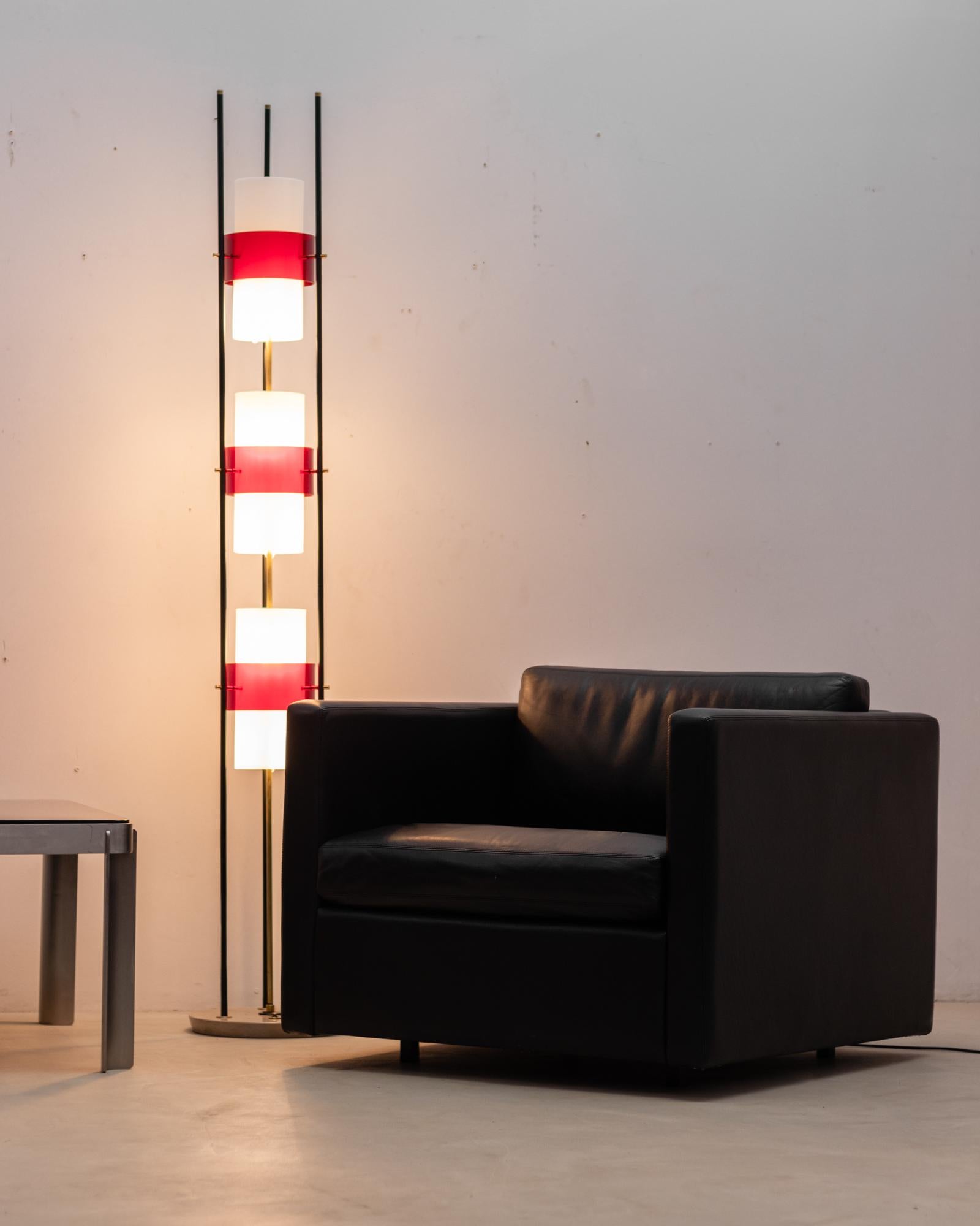 Transport yourself to the 1950s with this Italian floor lamp crafted by Stilnovo.  This lamp stands on a sturdy marble base, supporting three sleek, black painted uprights. These uprights act as the structural foundation for the lampshades, which