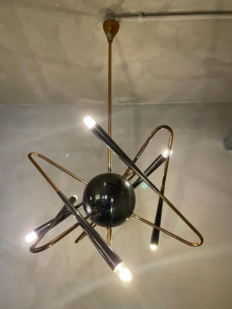 Sputnik chandelier manufactured by Stilnovo in Italy, 1950s.
Chandelier is held by a rigid brass rod that crosses the central sphere to form a spike in the final part.
Six brass arms, that give a sense of movement, depart from the central sphere