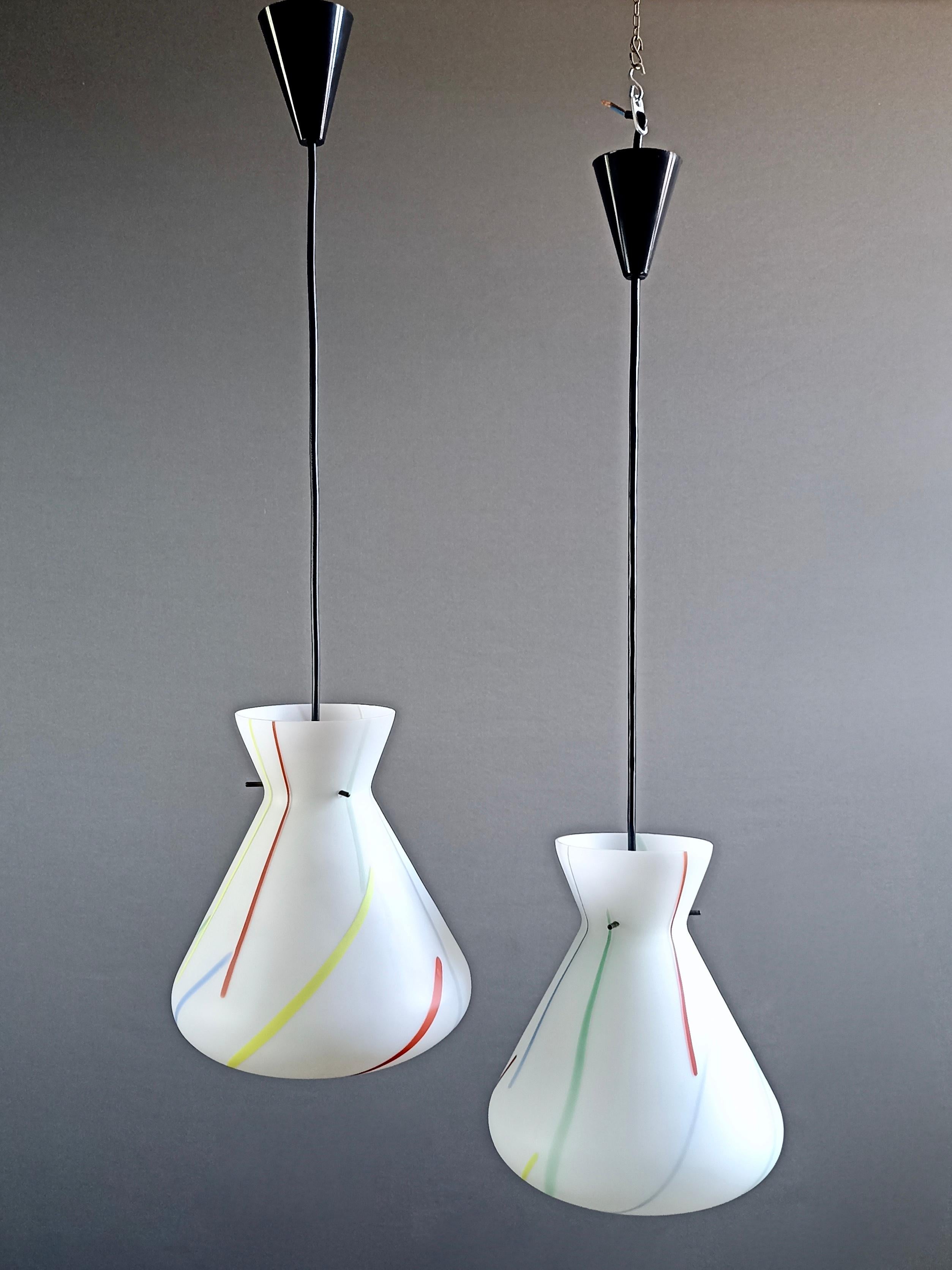 A charming pair of one-light multi-color glass ceiling lamps. Their elegant profile is characteristic of 1950s Italian design lamps and refers to Stilnovo style.
The twin lamps, with the same size and shape, are in cased white opaline matte Murano
