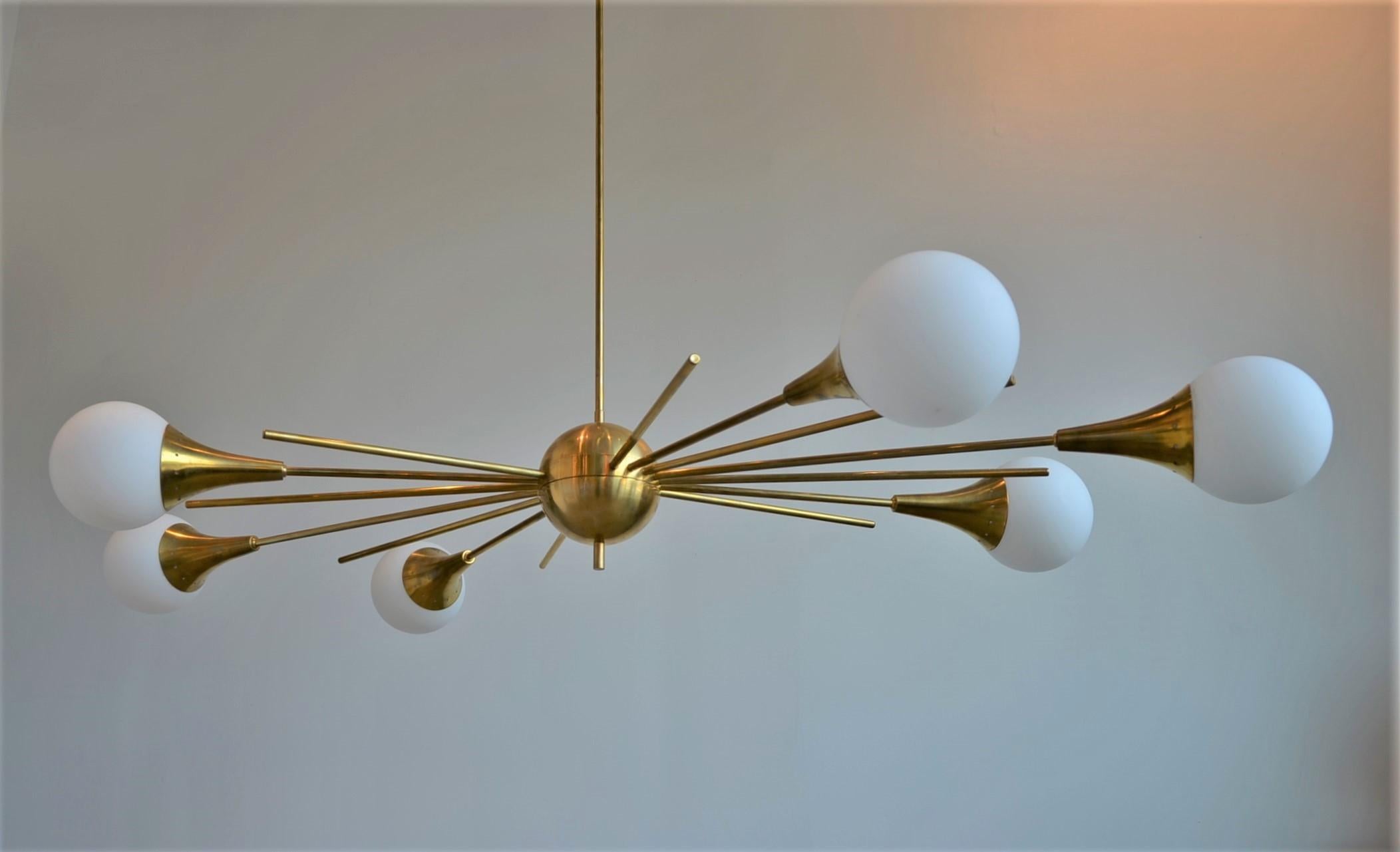 Offered is a Mid-Century Modern Italian Stilnovo style brass frame and six trumpet style arm / torchère with large white glass globes attached, Sputnik chandelier. The height is adjustable at 35.4