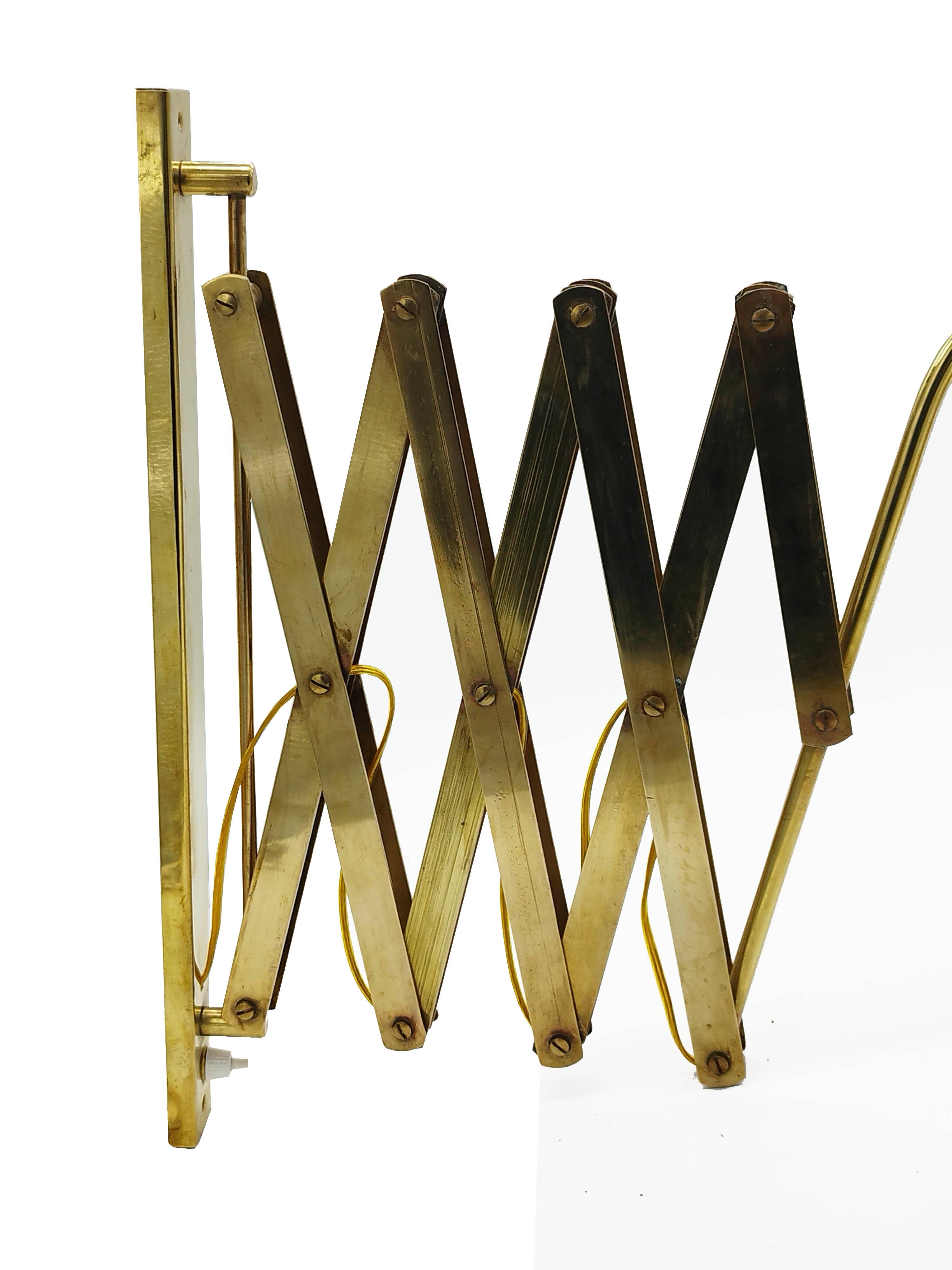 Scissor wall lamp produced in Italy in the 1950s. Entirely made of solid brass. The arm length is extendable and the shade can be swivelled up and down and the arm from left to right. Excellent original condition.