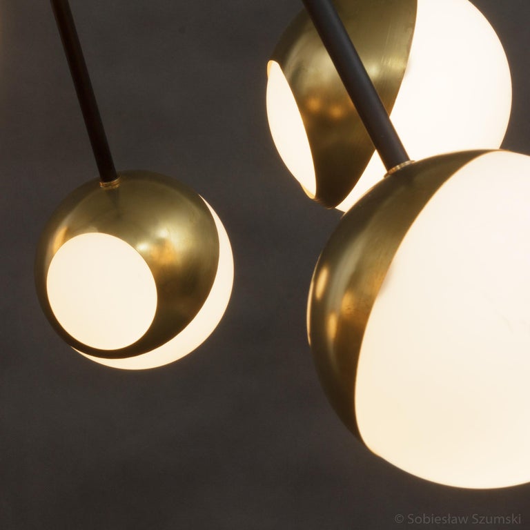 A large and impressive Italian midcentury chandelier with eight ball lamps in brass, black varished metal, and opaque glass. Polished brass very light patina. Very resemble of Stilnovo lamps the 1950s.