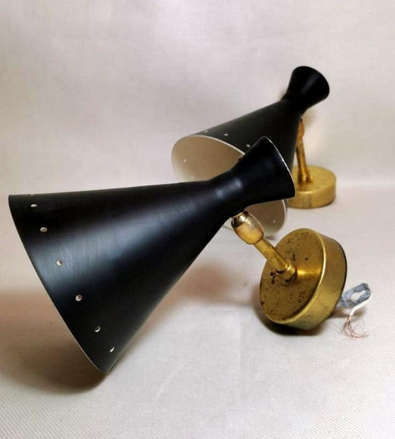 Pair of sconces in brass and black painted metal; they have only one light fitting, in the truncated cone part; in the middle have a joint that allows you to rotate them 360° according to your wishes or furnishing needs; the two brass end plates