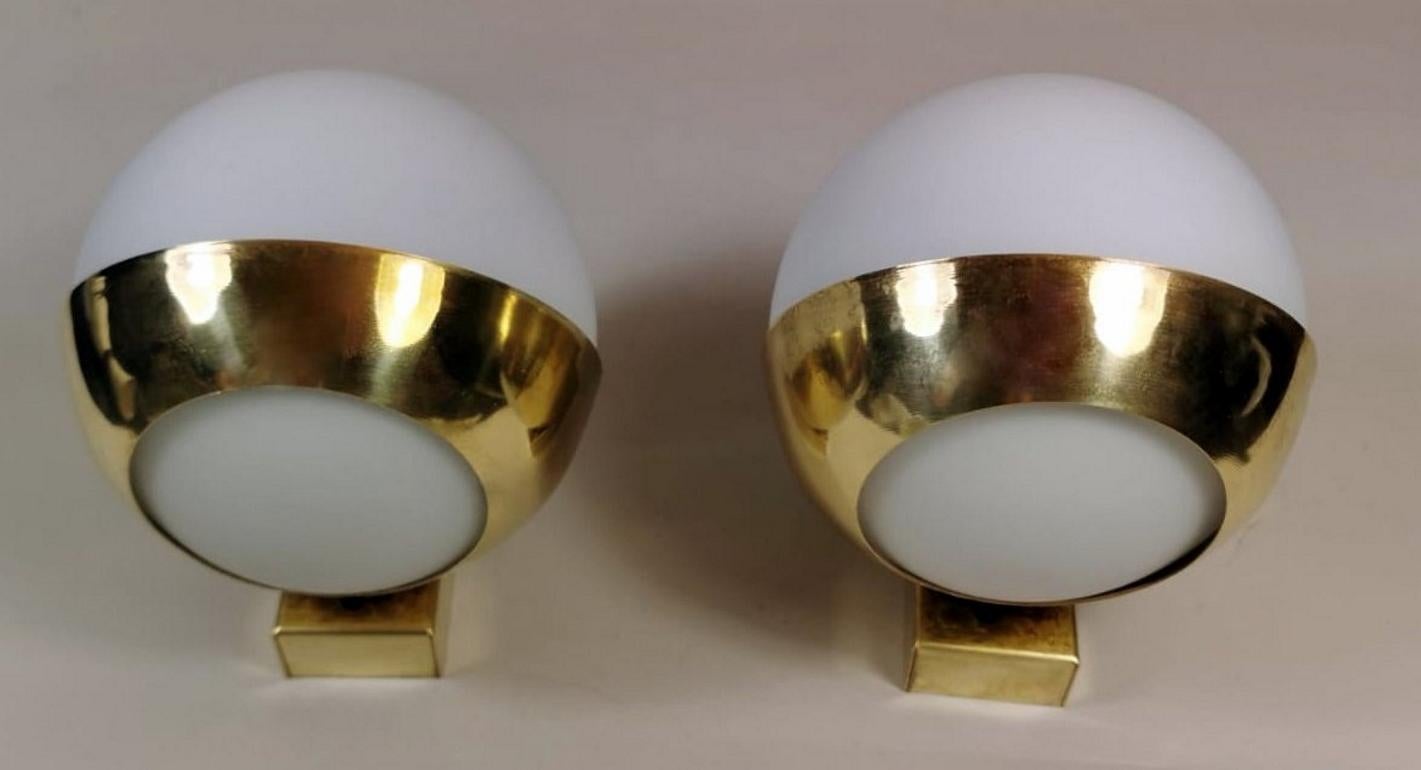 Pair of brass wall sconces with opaline glass ball diffusers; each one has a lamp holder inside; the particular and practical brass structure allows to divide the light and distribute it up and down with a delicate and pleasant effect; on the back