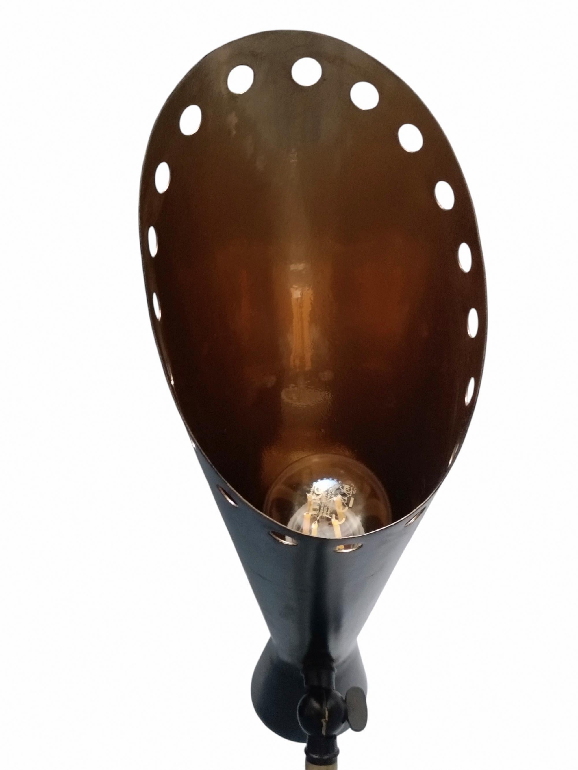 Lampada da terra con paralume conico in metallo nero forato e base a tre punte in ottone.
Il paralume conico in metallo nero con base e stelo in ottone offre una combinazione classica.