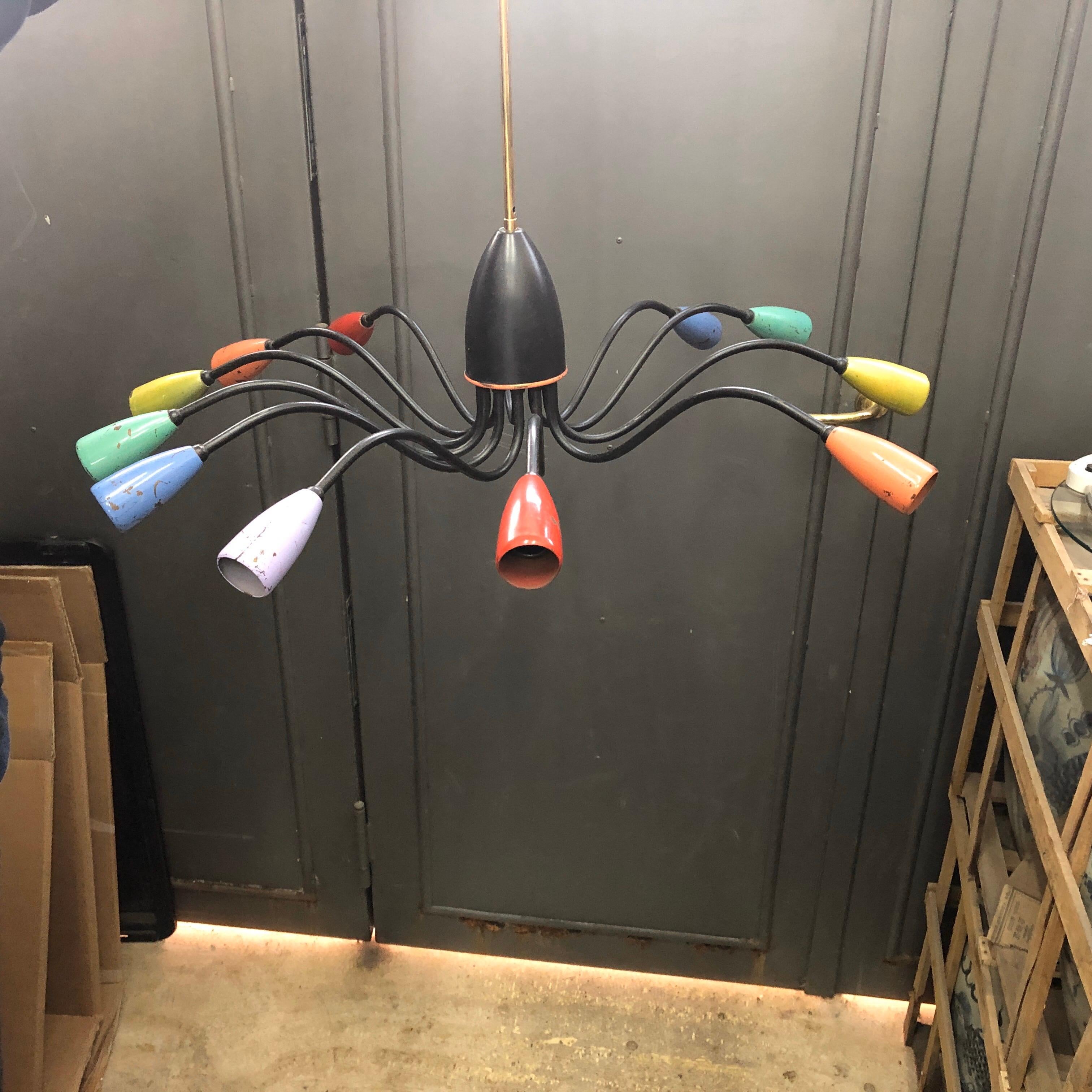 A multicolored ten lights Sputnik Italian chandelier in the manner of Stilnovo. It works 110-240 volts and needs 10 regular e14 bulbs. All original colors. This chandelier in the manner of Stilnovo is a striking and iconic piece, capturing the