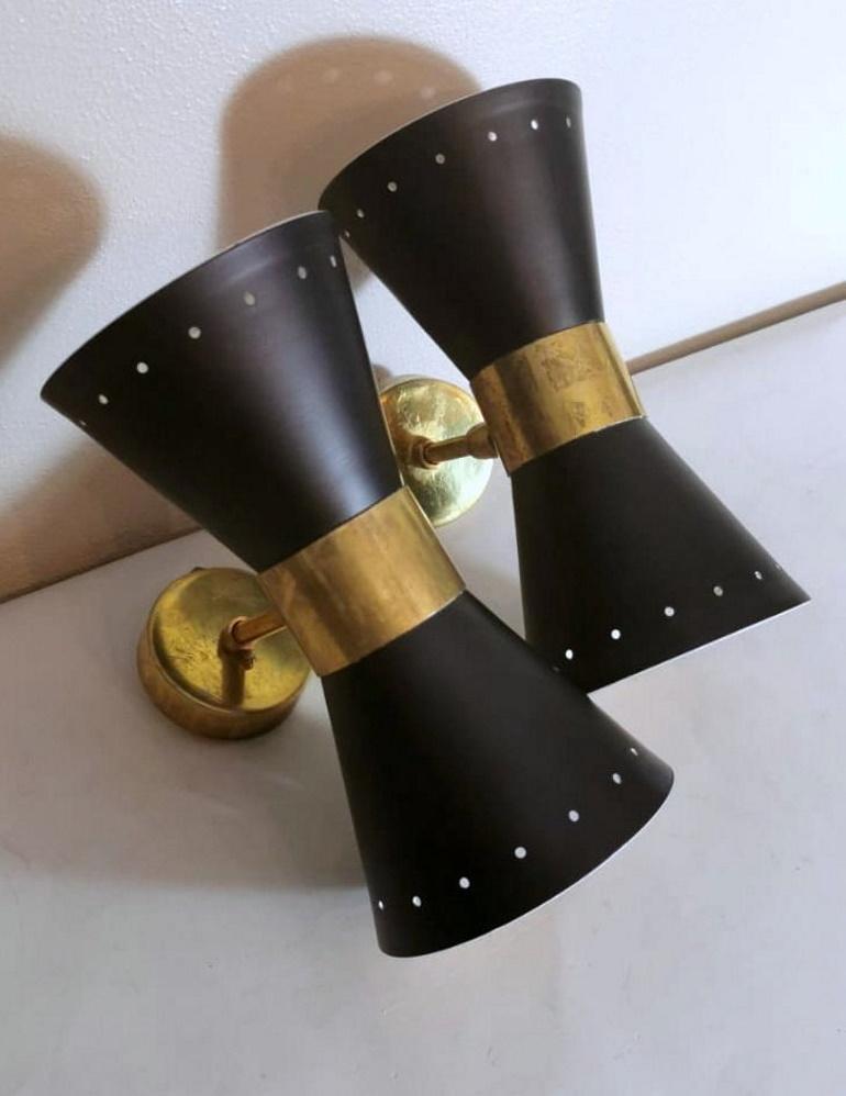 Pair of appliques in brass and metal painted externally in black and internally in cream white; they have two connections for direct and indirect light; in the middle, they have a joint that allows you to rotate them 360° according to your wishes or