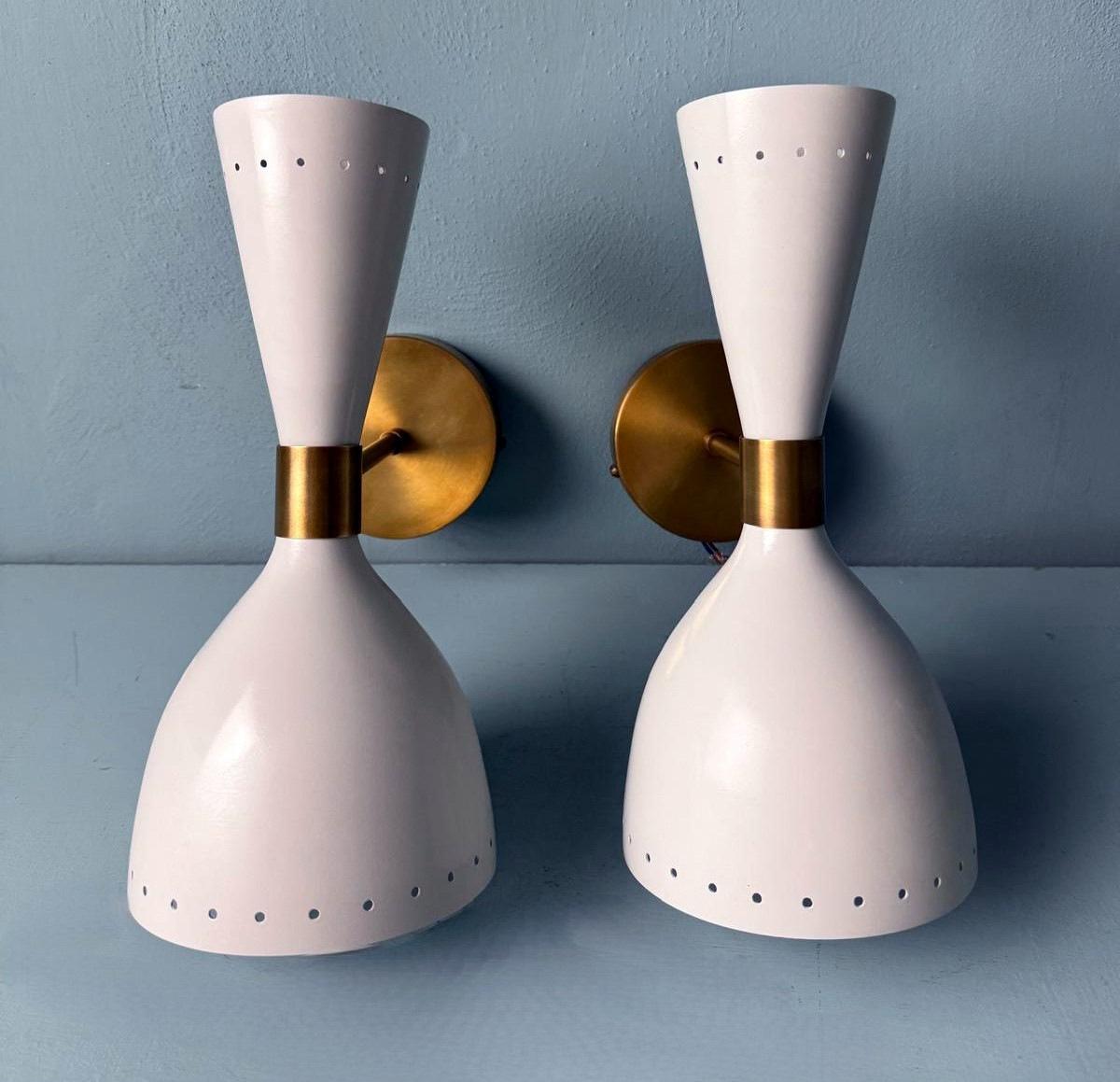 We kindly invite you to read the full description, as we have provided detailed technical and historical information to ensure the authenticity of our items.
This iconic and elegant pair of wall lights is crafted in brass and features two opposing