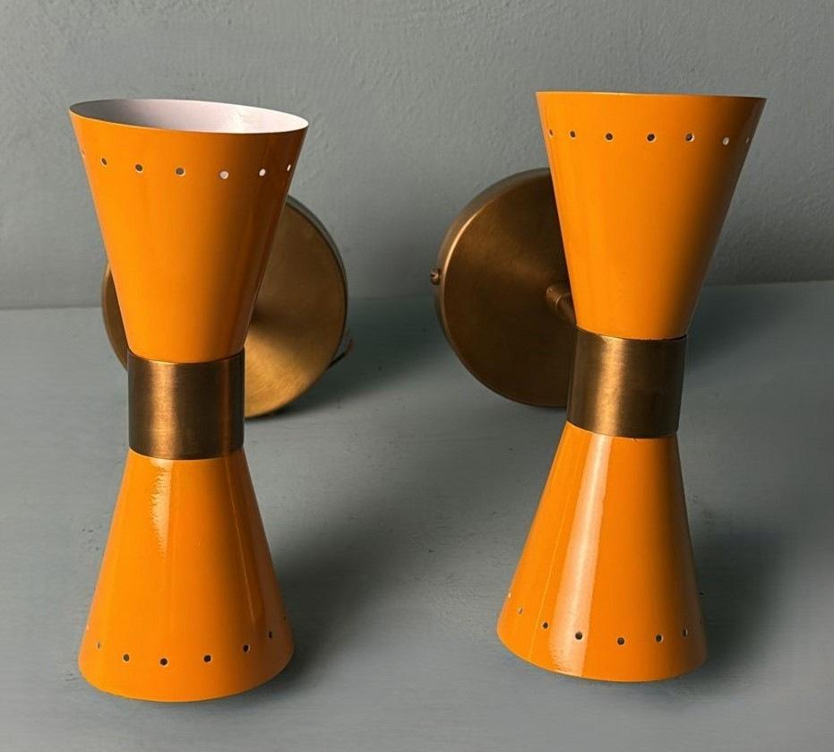 We kindly invite you to read the entire description, as we have provided detailed technical and historical information to ensure the authenticity of our items.
Iconic and refined pair of wall sconces crafted in brass and featuring two opposing