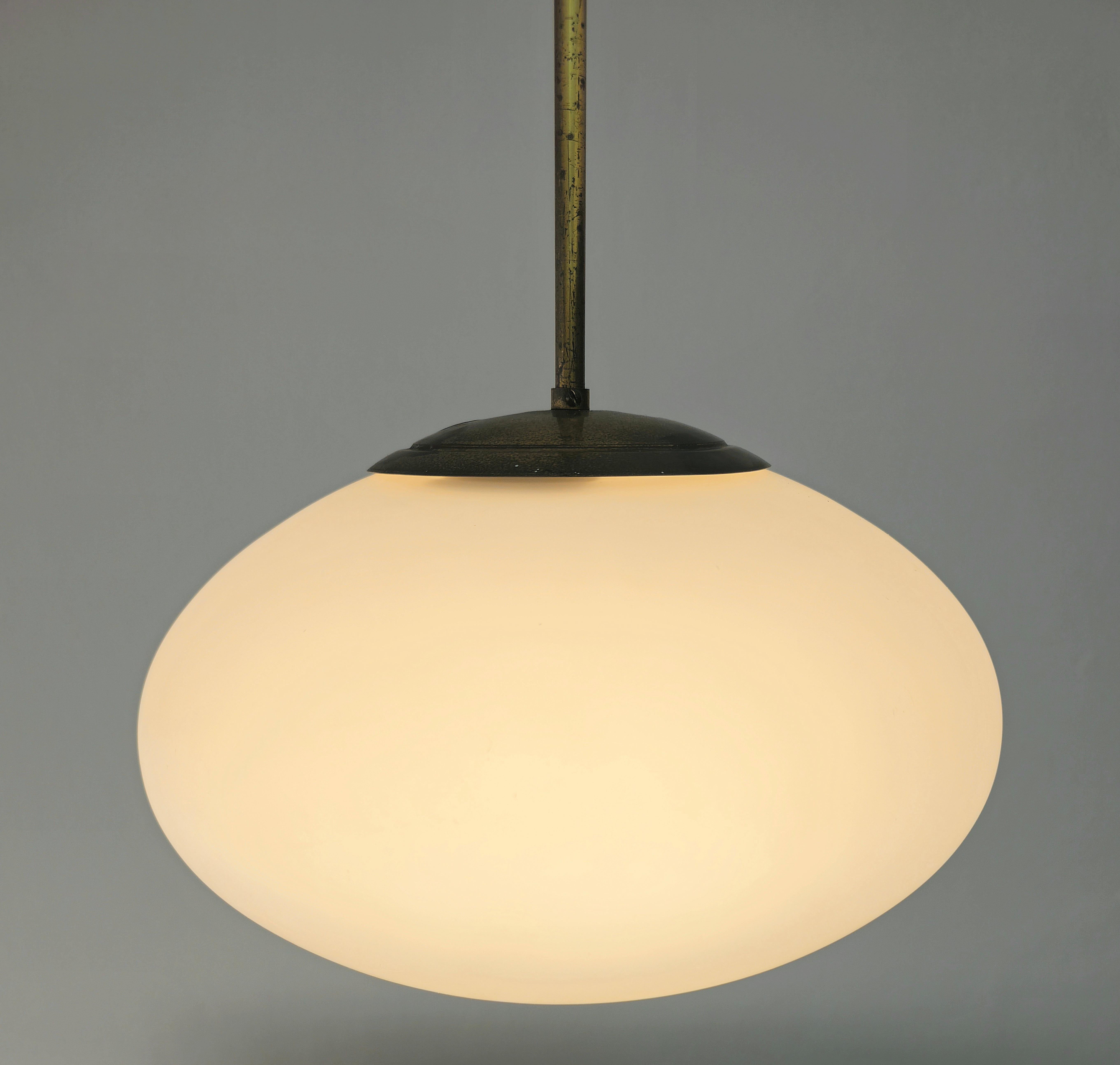 Die Hängeleuchte hat einen ellipsenförmigen Opalglasdiffusor. Das Glas wird von einem Messing-Zubehörteil getragen, das das Glas ermöglicht. Alles wird von einem Stahldraht mit einer Rosette aus Messing gestützt. für Design-Liebhaber empfehlen wir