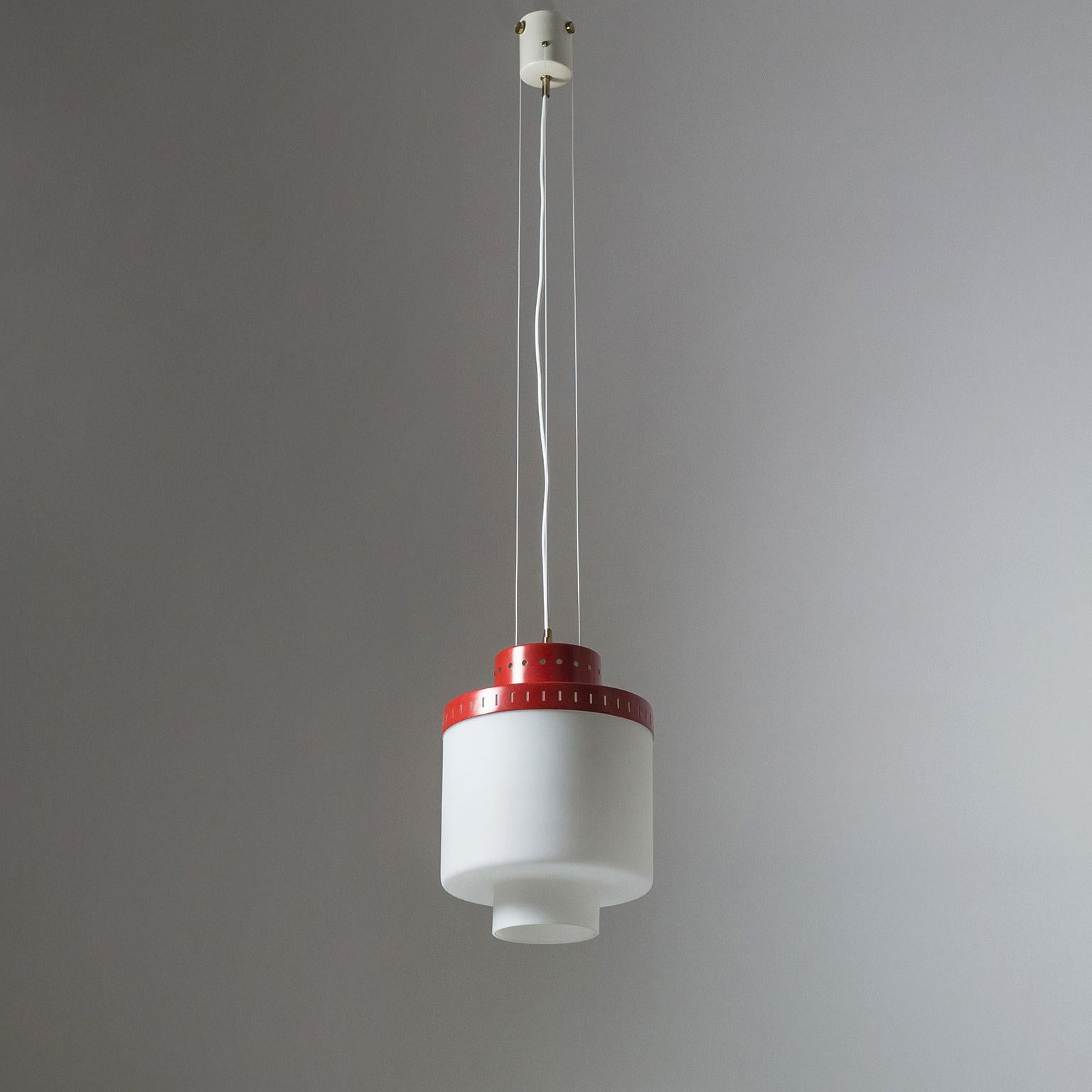 Rare Stilnovo suspension light from the early 1950s. A cylindrical, tiered satin glass diffuser with a red lacquered and pierced aluminum shade is suspended by three nylon wires. Very good original condition with minor loss of original paint and a