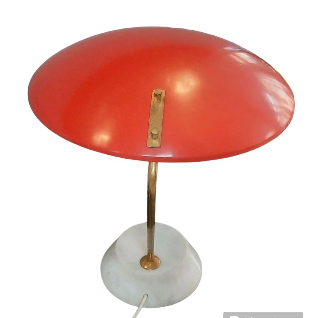 Élégante lampe de table conçue par Bruno Elegta et produite par Stilnovo.
Fonctionnement parfait.
La lampe présente un abat-jour en aluminium laqué rouge avec une tige en laiton sur un socle en marbre blanc de Carrare. Production italienne à partir