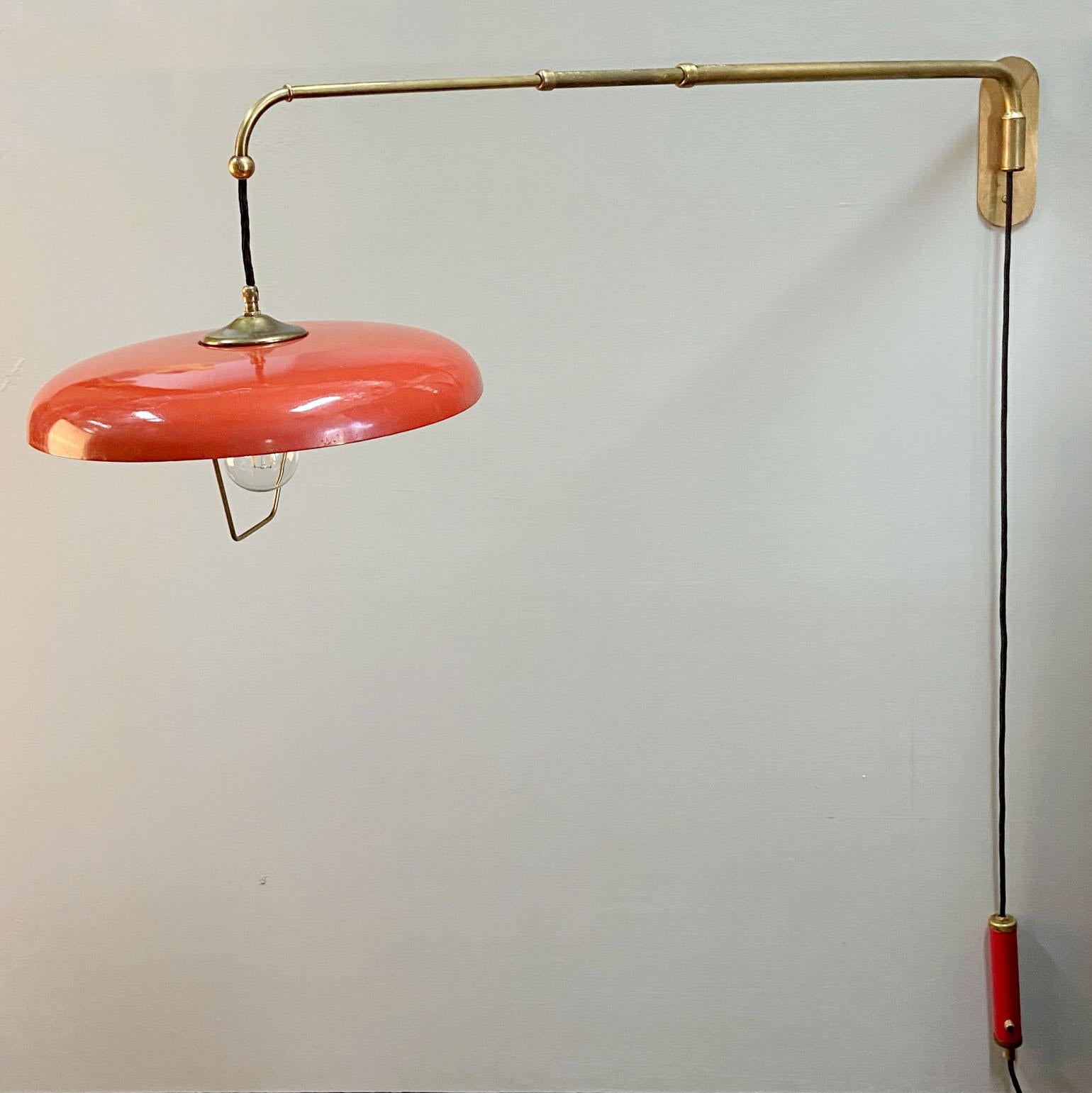 Original Mid-Century Modern 1950's telescoping adjustable wall mounted lamp with counterweight is attributed to Stilnovo. The lamp is fully adjustable. The tomato red metal shade is connected to a brass pole in 3 parts that allows to extended