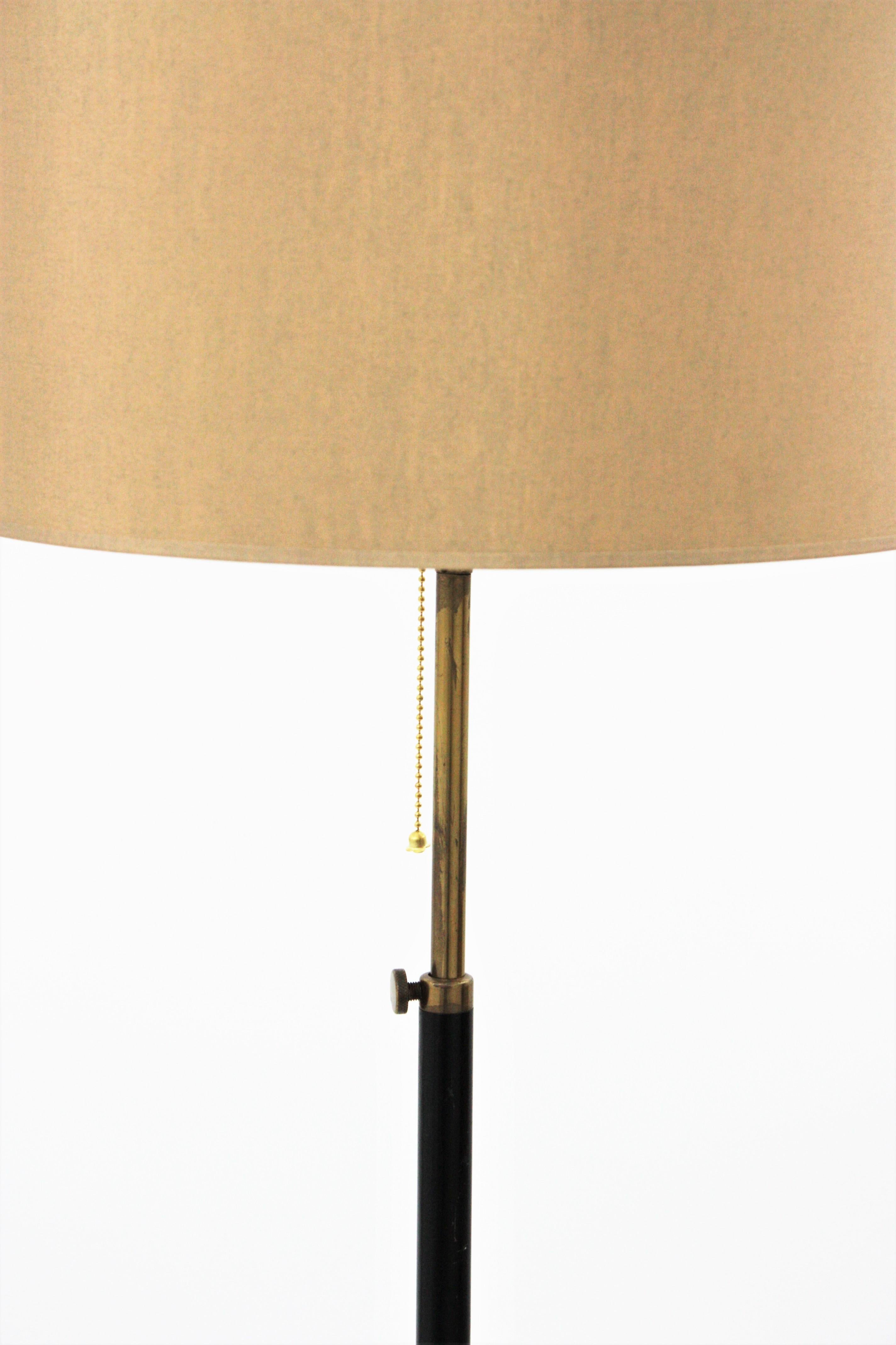 A black lacquered metal and brass adjustable tripod floor lamp attributed to Stilnovo, Italy, 1950s.
The metal stem is finished in black lacquer and it stands on a tripod base, the telescopic shaft allowing to adjust the height, which can vary