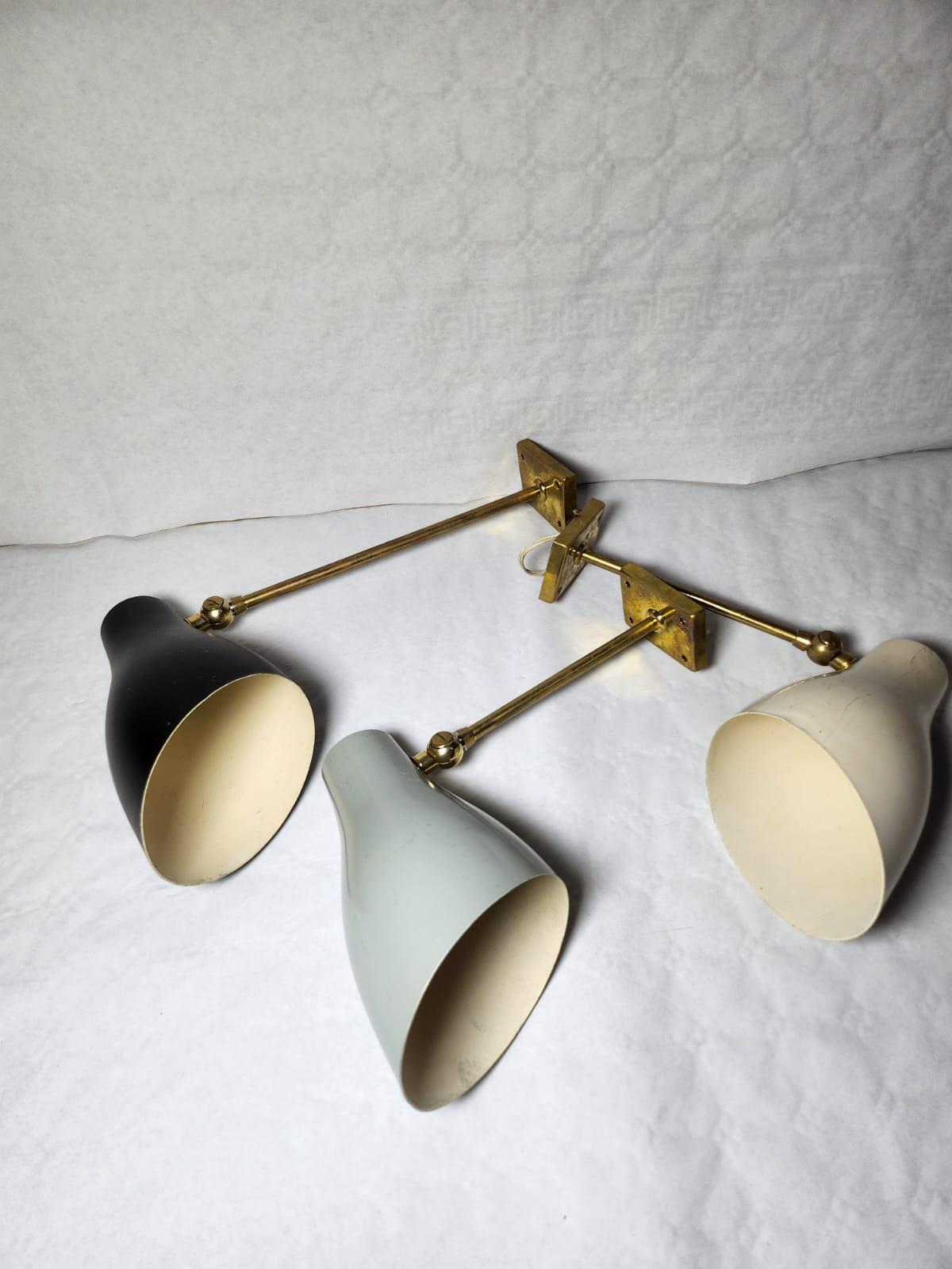 Wonderful trio of wall sconces by Stilnovo in polished brass and enameled aluminum shade,  black, beige and gray.
The measurement from the wall is 30 cm for the smallest, and 45 cm for the largest. They are in very good condition, with original