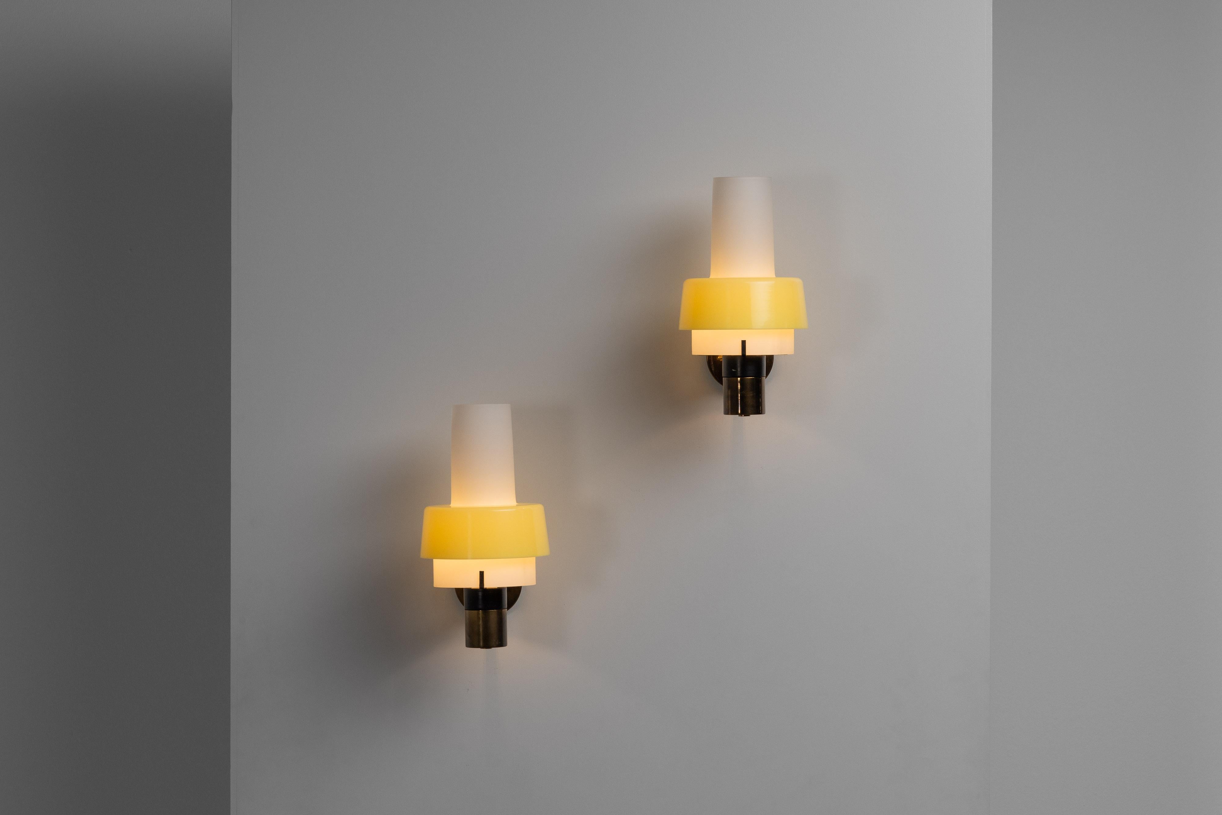 The model 2079/1 wall lamps, designed and manufactured by Stilnovo in Italy in 1960, are exemplary pieces of mid-century modern lighting design. Each lamp features a solid brass structure, which lends a timeless elegance and durability. The brass