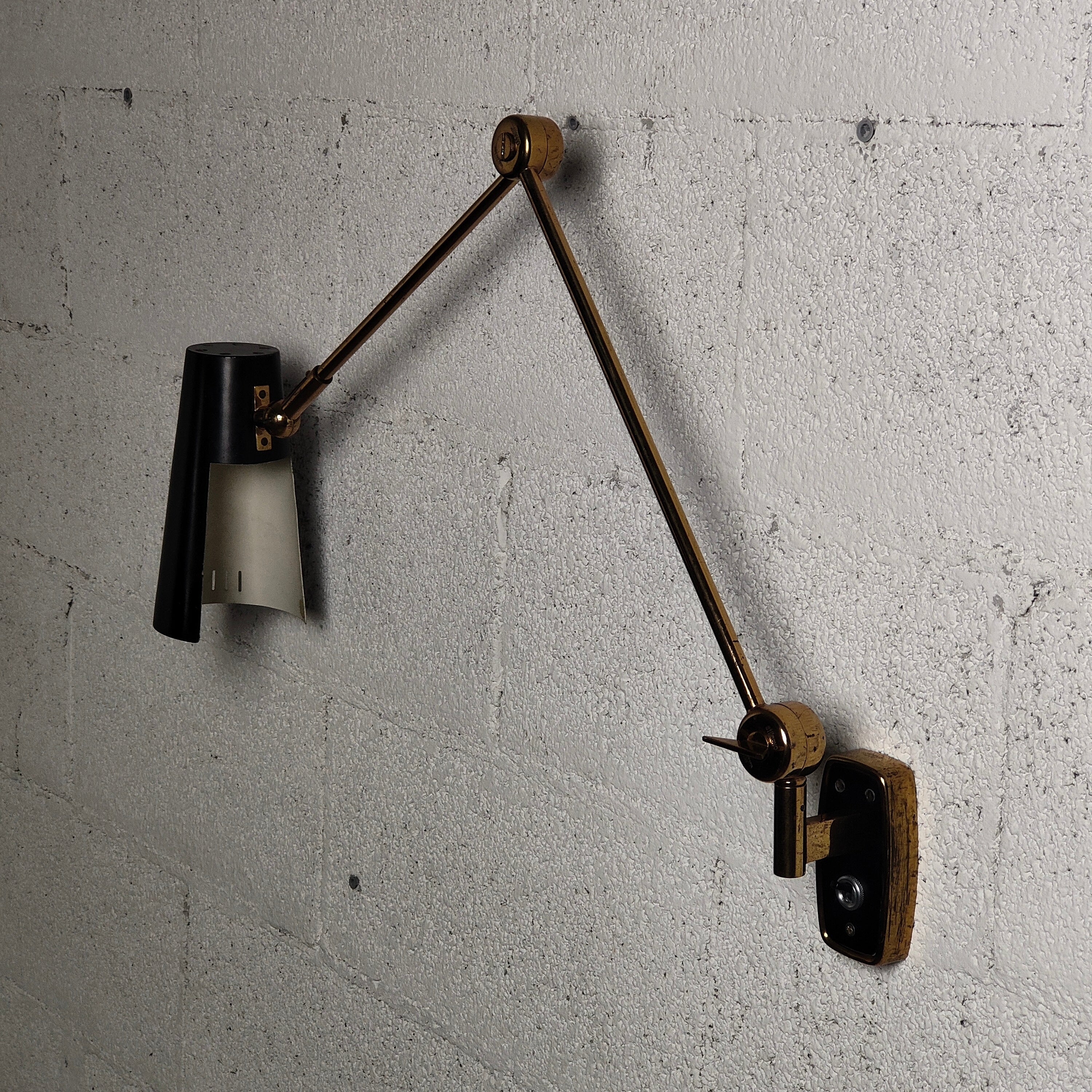 Stilnovo articulating wall light model 2024 with black enameled perforated metal shades on brass arms, Italy, 1960s. 
The metal shades pivot from ball joints and the articulating arms are adjustable from butterfly keys. 
Beautifully designed and