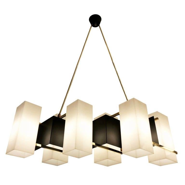 Elongated chandelier manufactured by Stilux in the 1960s featuring six rectangular perspex shades on a sloping frame. The frame is lacquered black with brass accents that connect to the canopy via two angled stems. Perfect over a dining table. Holds