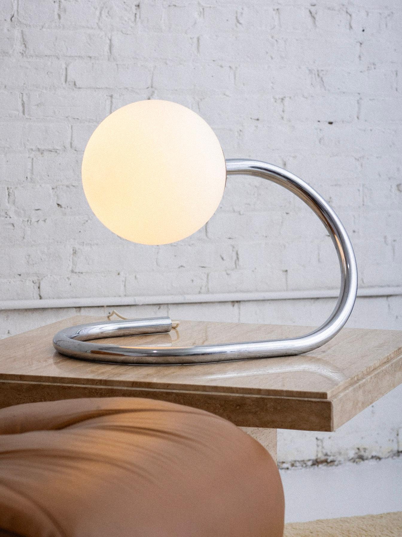 An Italian mid century table lamp by Stilux. A serpentine tubular chrome chrome arm supports a frosted white glass globe. Retains part of the original ‘Stilux’ sticker. Globe measures 10” in diameter. 